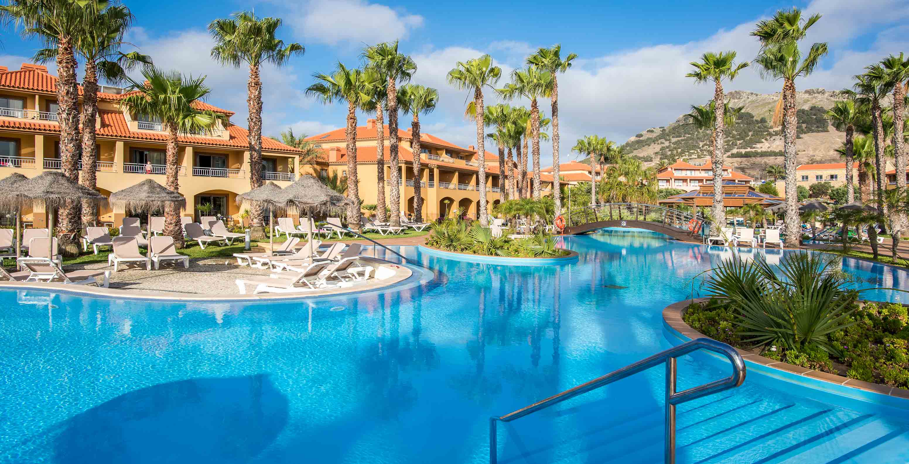 Pestana Porto Santo pool view with palms, colorful buildings under blue sky