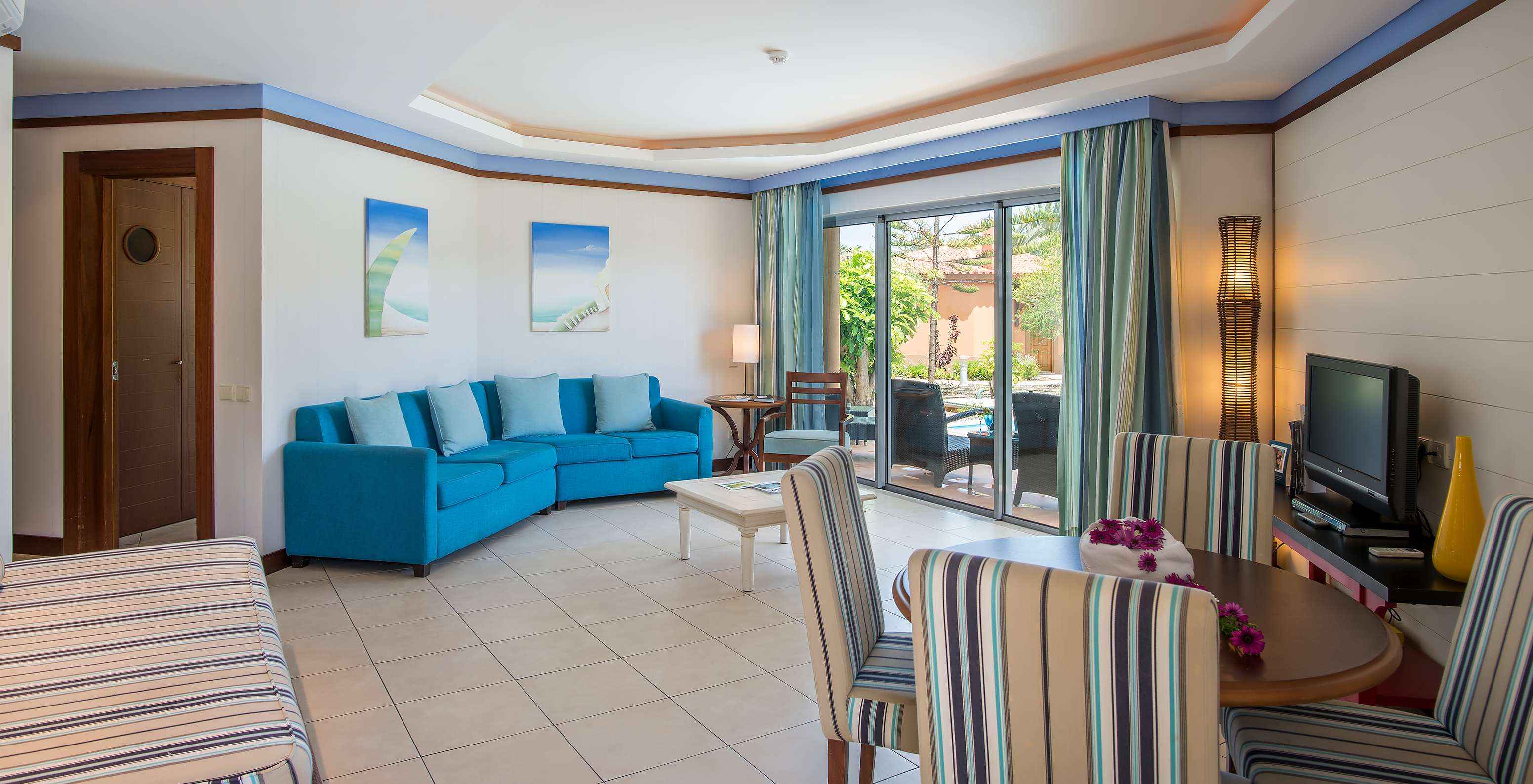 The Pool Villa of Pestana Porto Santo All Inclusive has a living room with a window, table and chairs, sofa, and a television