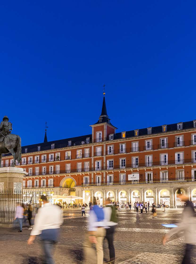 Plaza Mayor, in the historic center of Madrid, at night, with many tourists waljing around the Pestana Plaza Mayor is located
