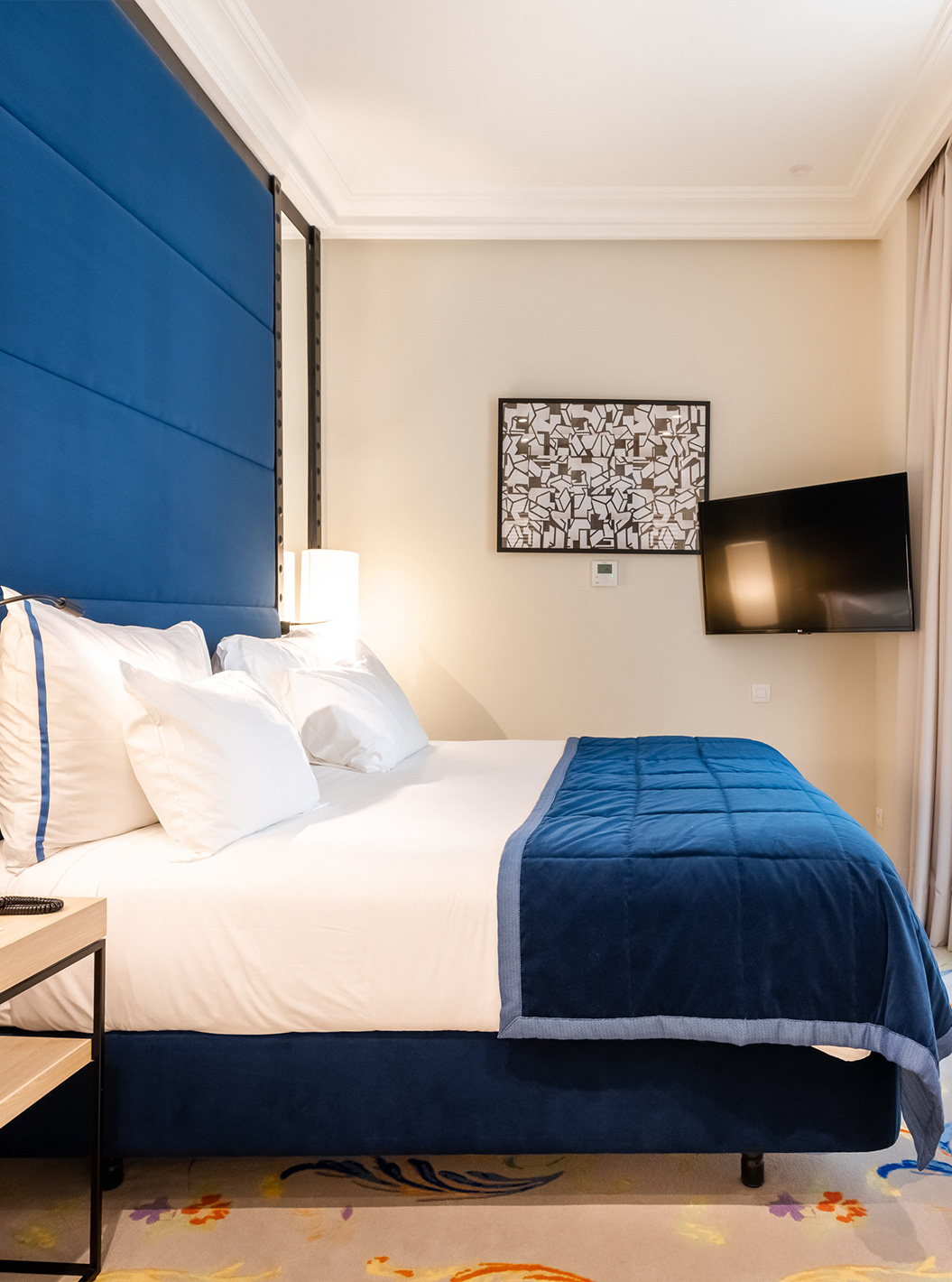 The Superior room at Pestana Plaza Mayor Madrid has a double bed, a blue headboard, a television and mirrors
