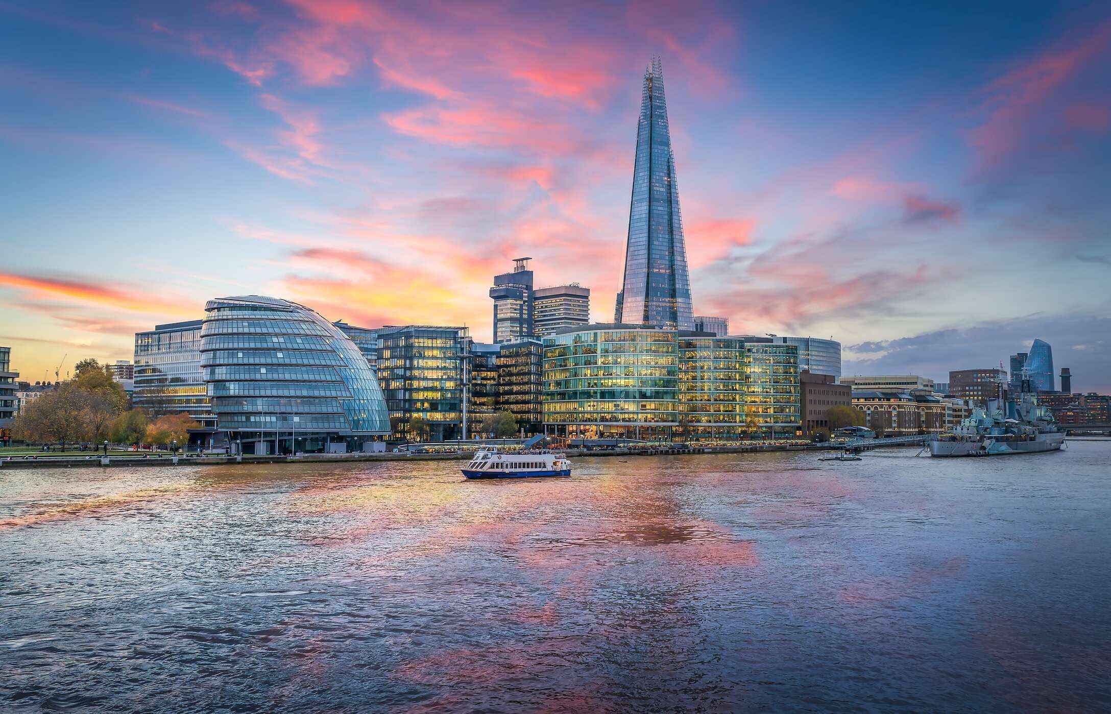 Panoramic view of The Shard at sunset, with a boat sailing on the Thames River in London, United Kingdom.