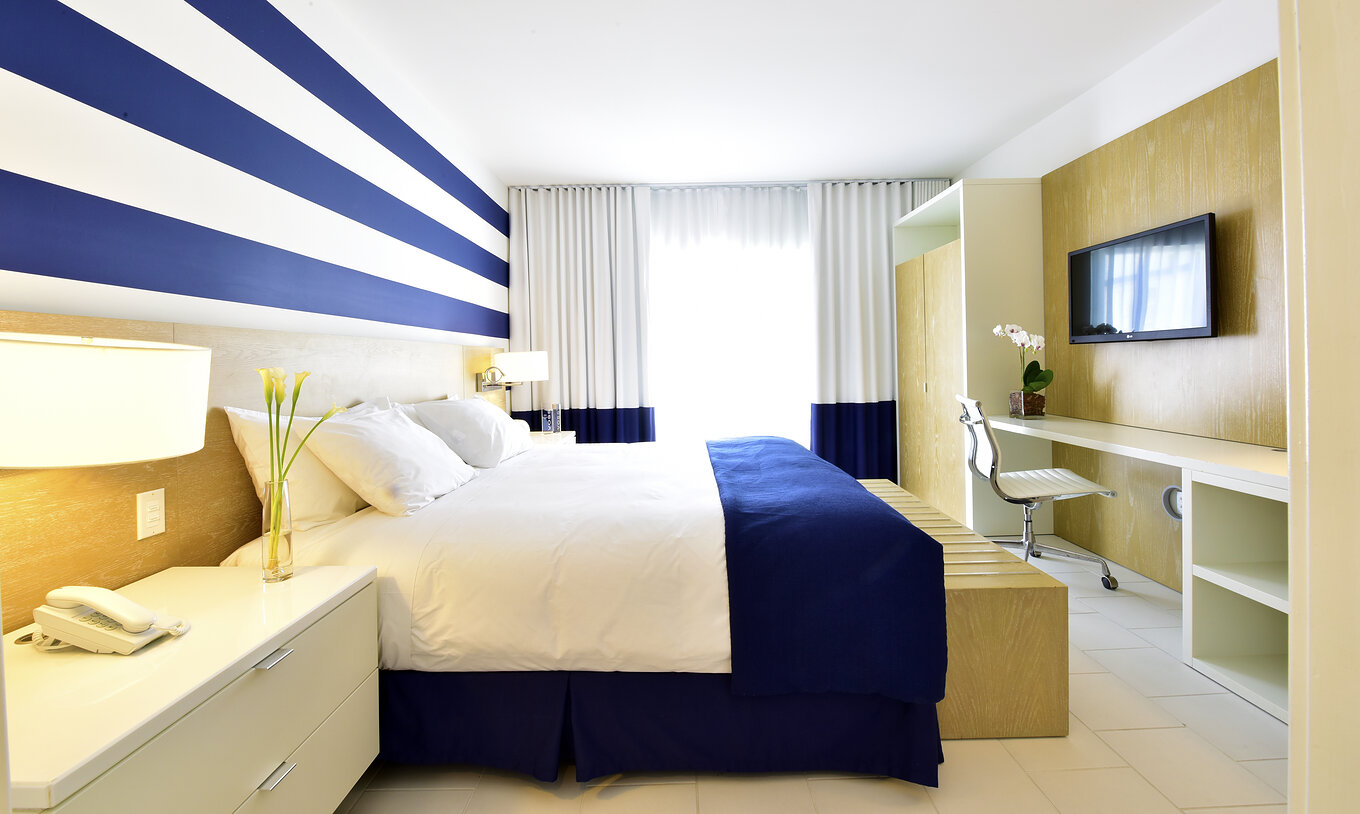 The Two Bedroom Suite with Balcony at Pestana Miami South Beach has a double bed, closet, TV and table