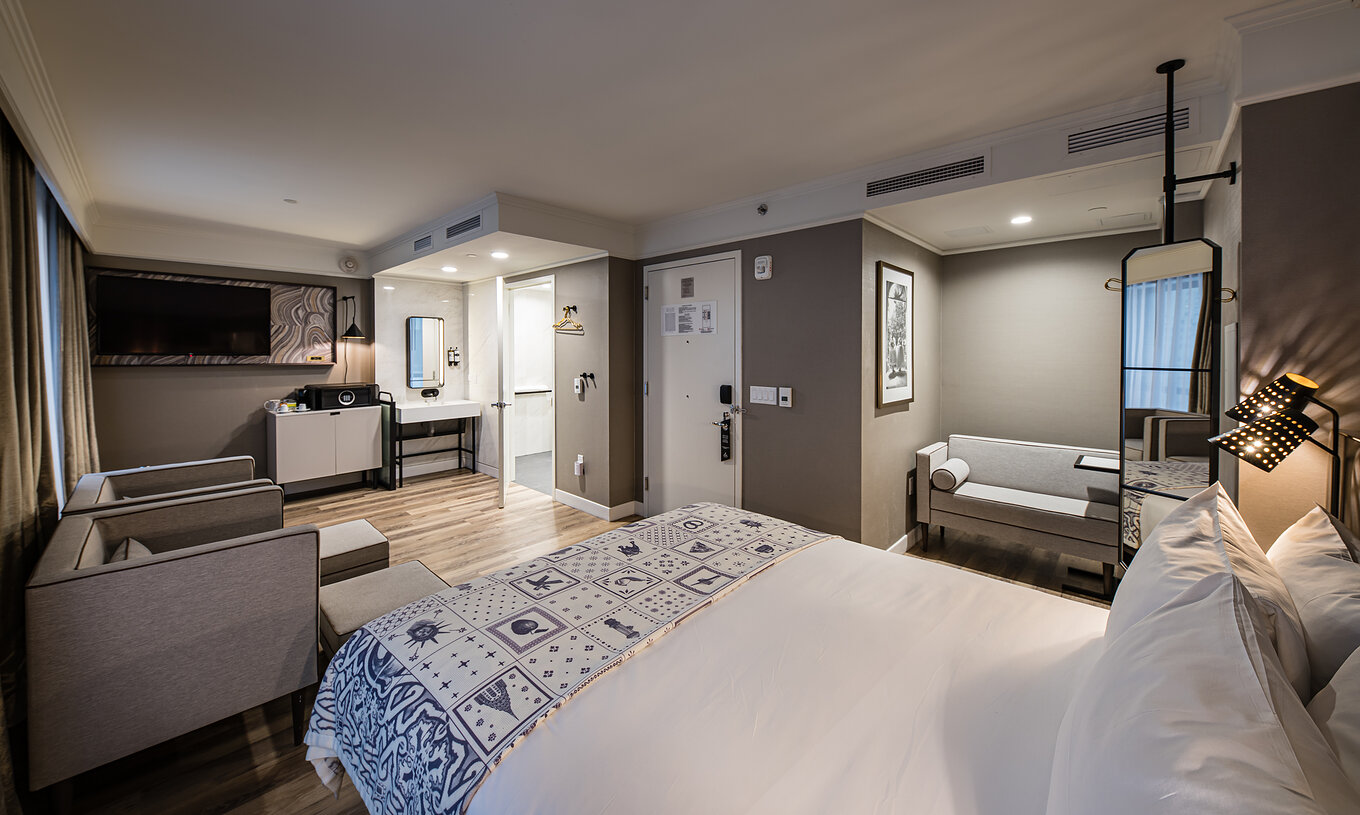 The Junior Suite - ADA at Pestana Park Avenue has a living room with sofa and armchairs, safe and TV