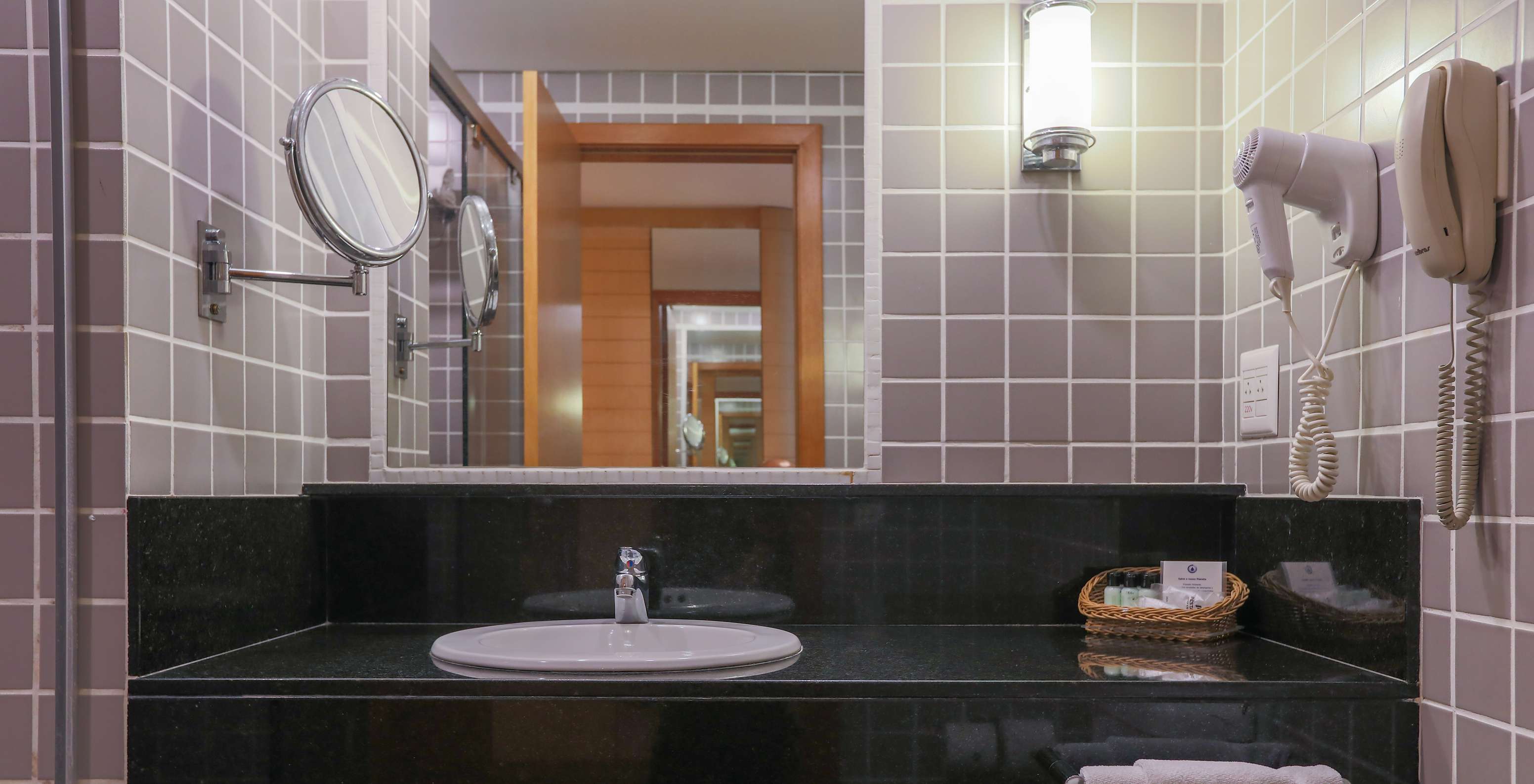 El Deluxe Corner del Pestana Curitiba tiene un baño con azulejos grises y un lavabo negro