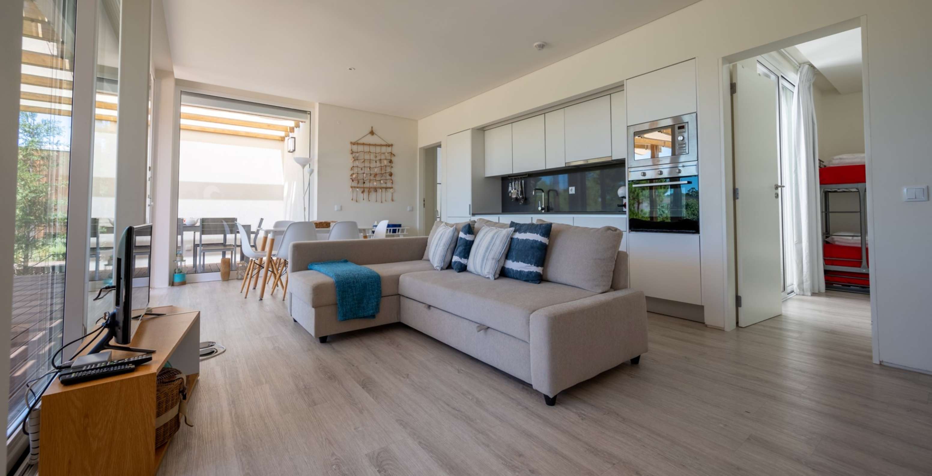 La Green Villa con Piscina Privada del Pestana Tróia Eco Resort tiene una sala junta con la cocina, sofá, mesa y televisión