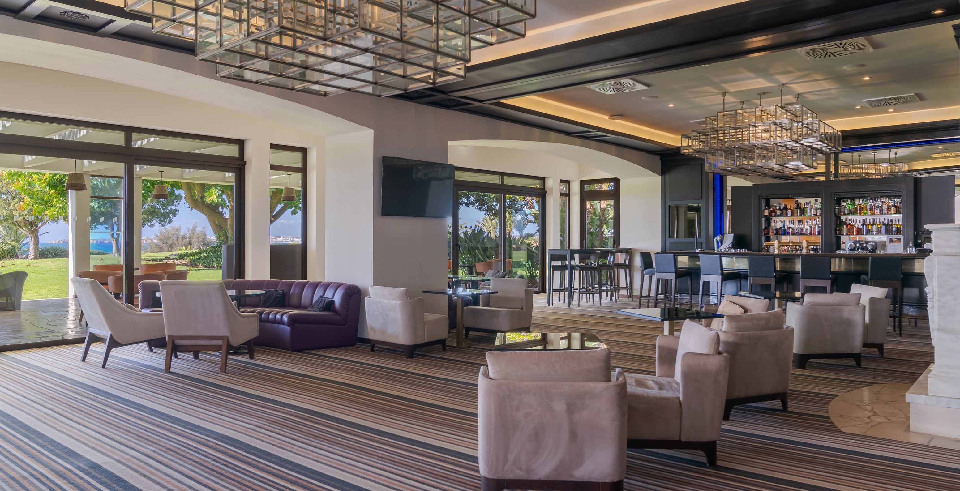 El bar D Henrique, del Hotel 5 Estrellas en Algarve, con sofás y sillones para disfrutar de bebidas y vista al mar y jardín