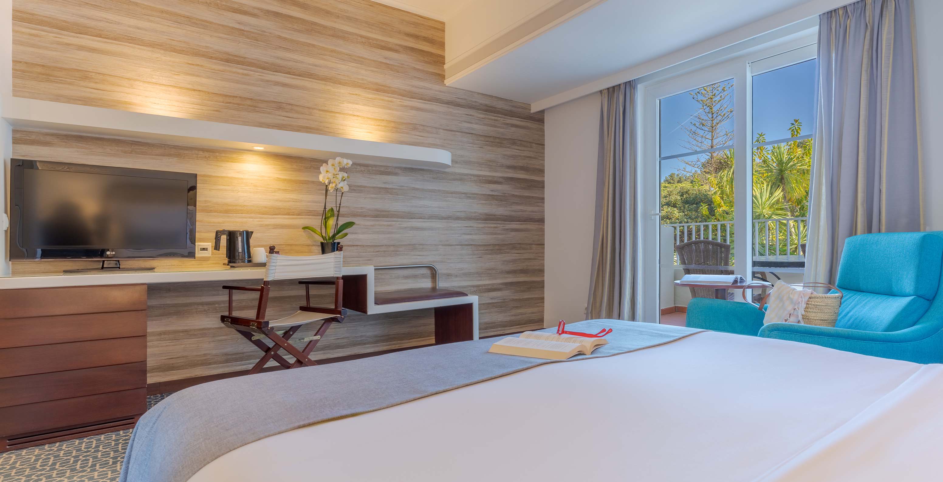 El Deluxe del Pestana Alvor Praia tiene cama matrimonial, televisión en el escritorio, sillón azul y ventana a la terraza