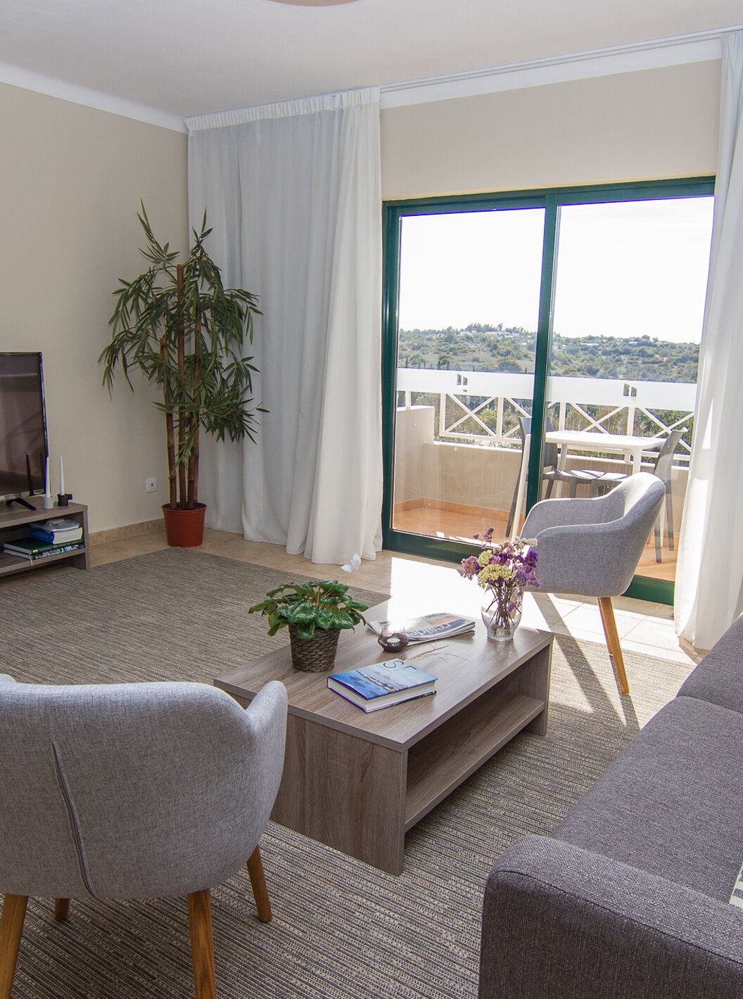 El Apartamento T2 del Pestana Gramacho Residences tiene una sala de estar con sofá, televisor y una ventana con un balcón