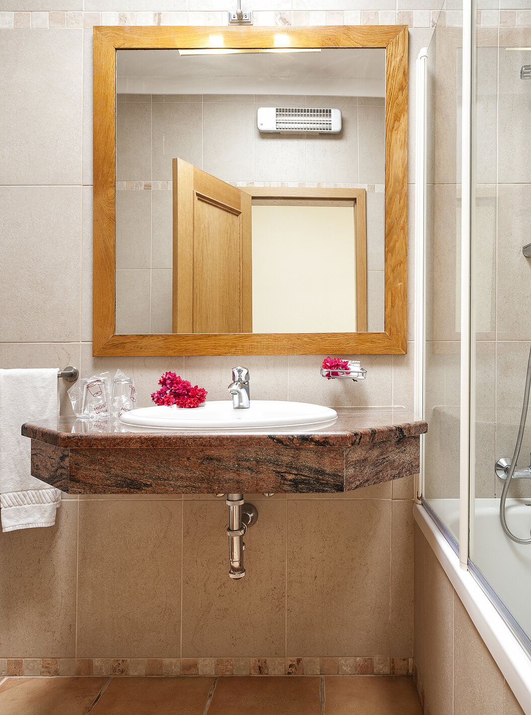 El Apartamento T1 - Terra del Pestana Palm Gardens tiene una bañera con ducha, un lavabo con flores y un espejo