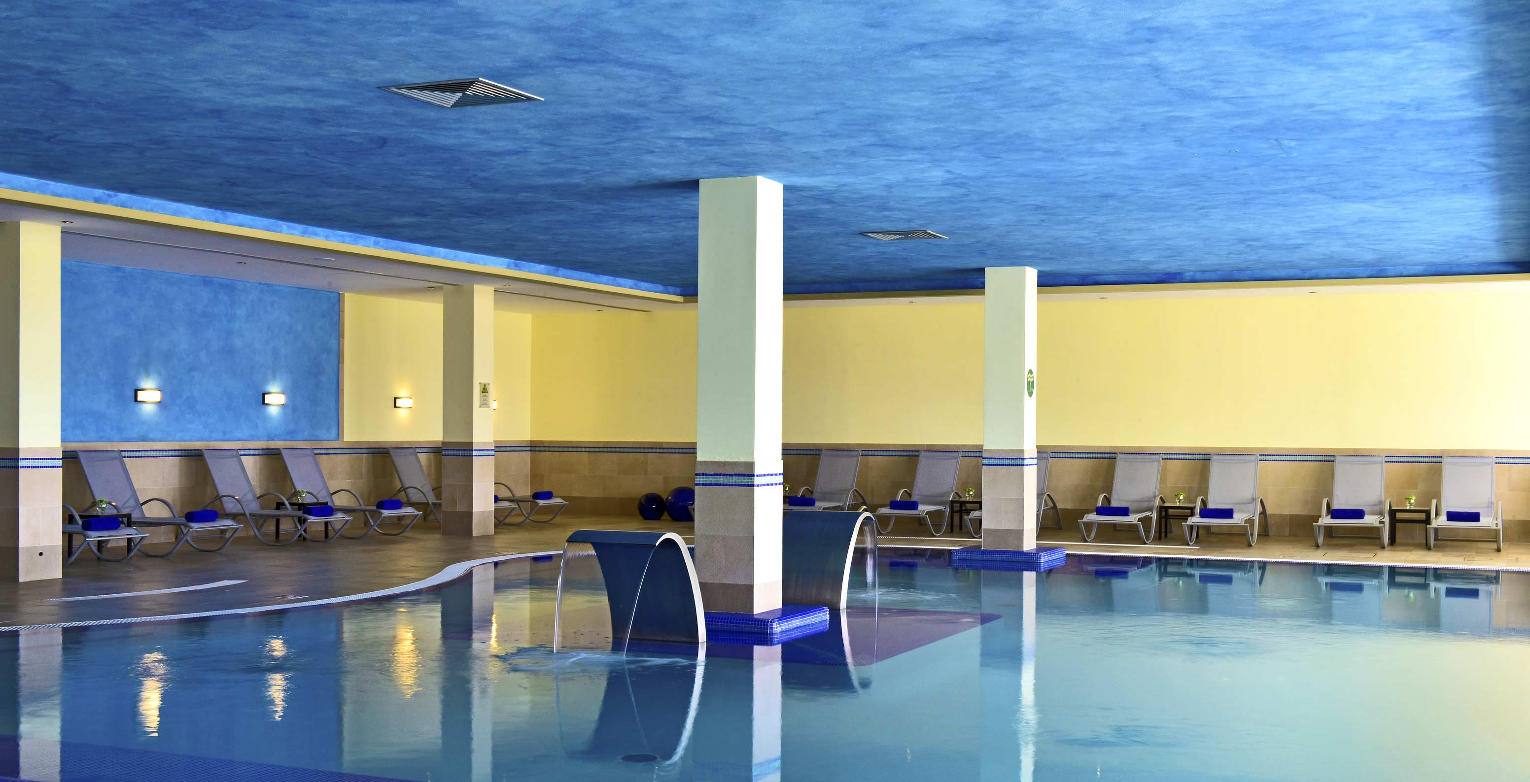 Piscina interior del Pestana Viking, paredes azules y amarillas, ambiente tranquilo, con varias tumbonas