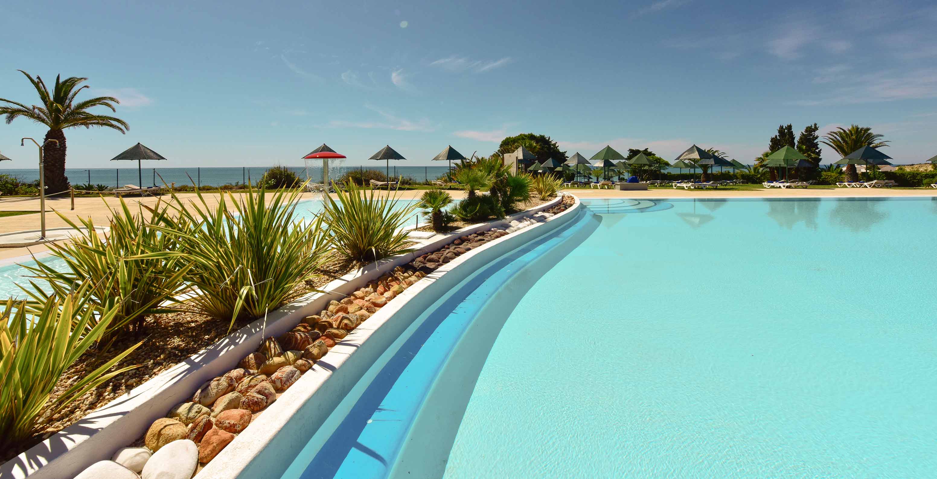 Piscina exterior del Pestana Viking, rodeada de vegetación, con tumbonas y vistas al mar