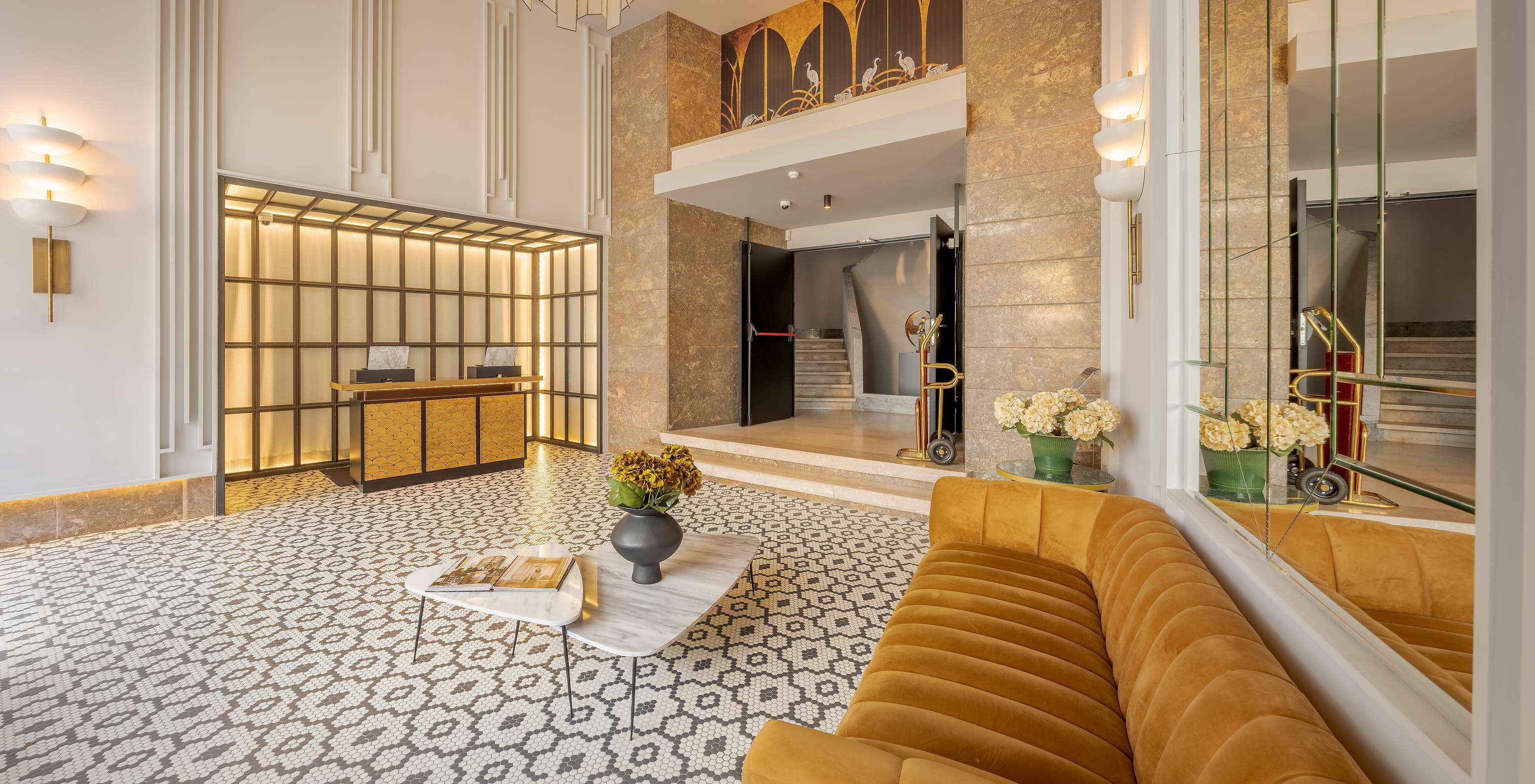 Lounge de recepción con una pareja y un niño, sofás y mesas con jarrones de flores y recepción