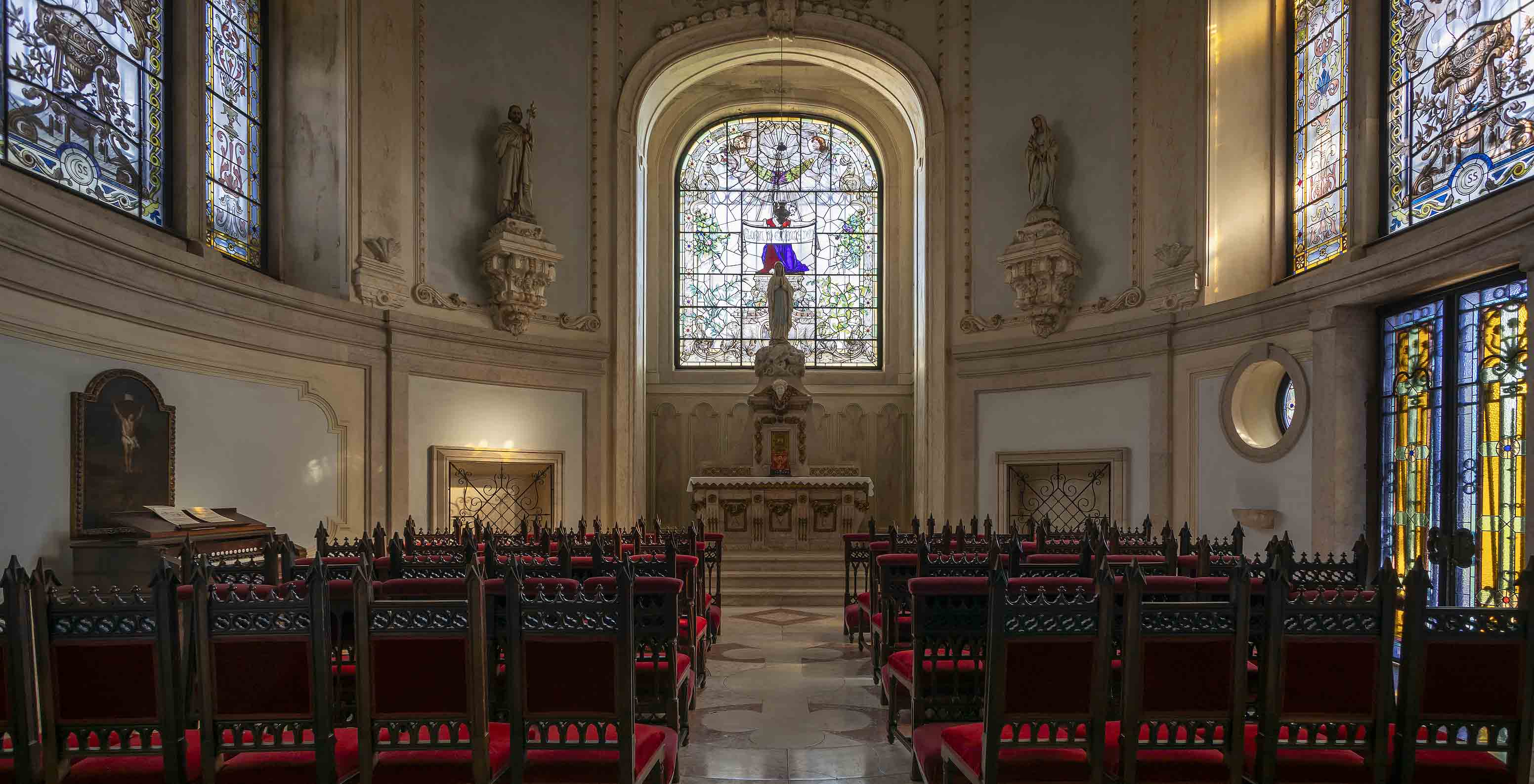 El Pestana Palace Lisboa tiene una capilla con un pequeño altar, varios vitrales y sillas de madera oscura
