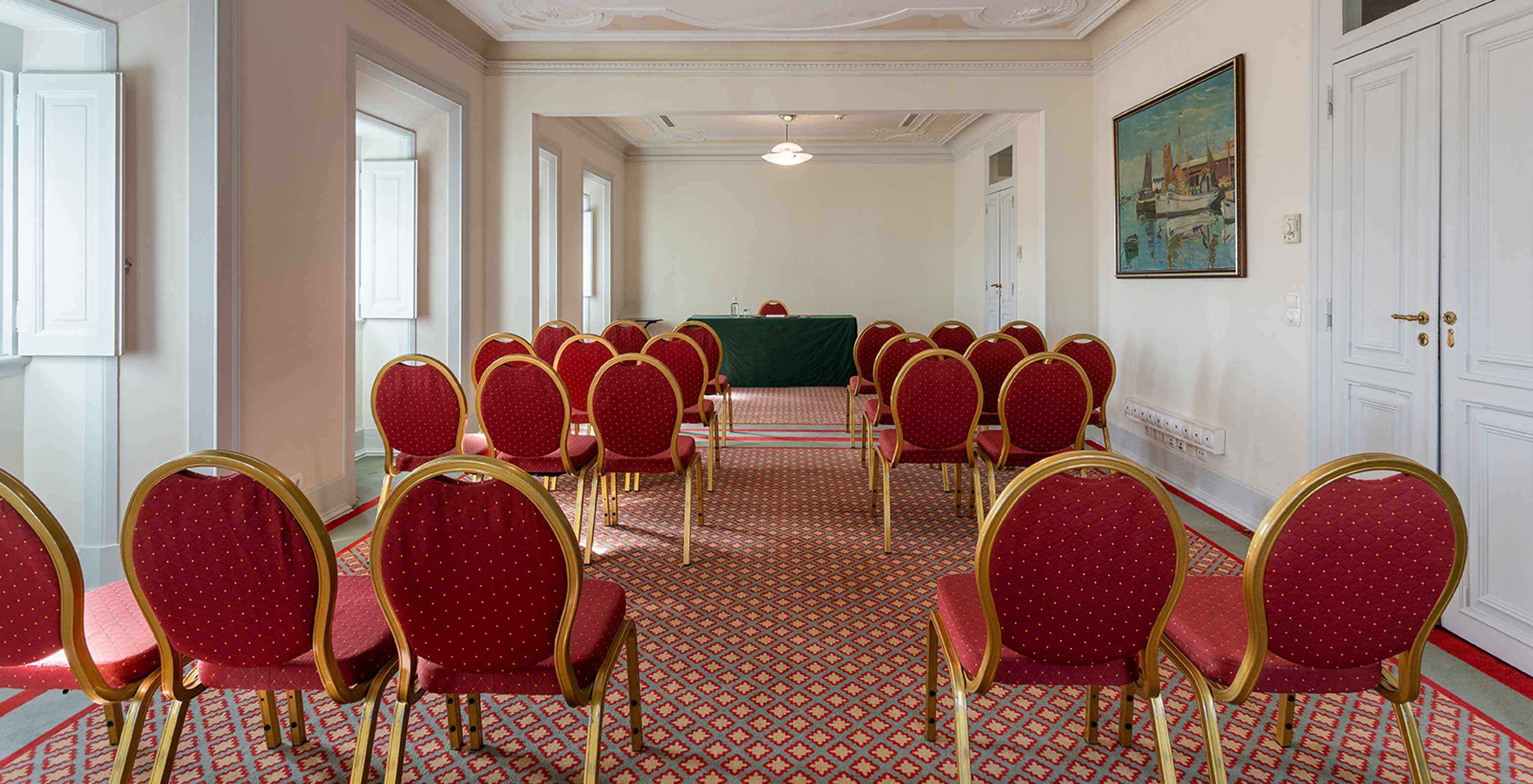 El Pestana Palace Lisboa tiene una sala de reuniones con varias sillas rojas y mesa verde rectangular