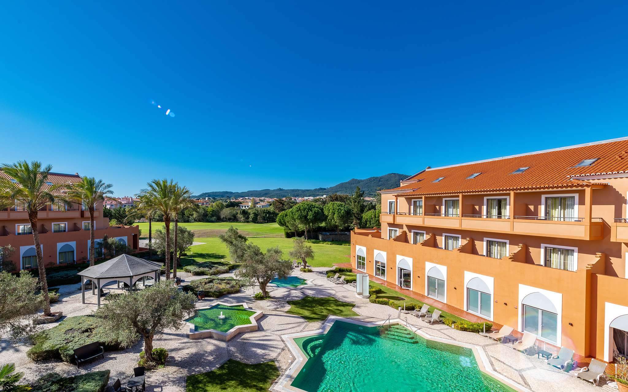 Vista de Pestana Sintra Golf, hotel de 4 estrellas en Sintra, con piscina exterior, jardín con árboles y un campo de golf