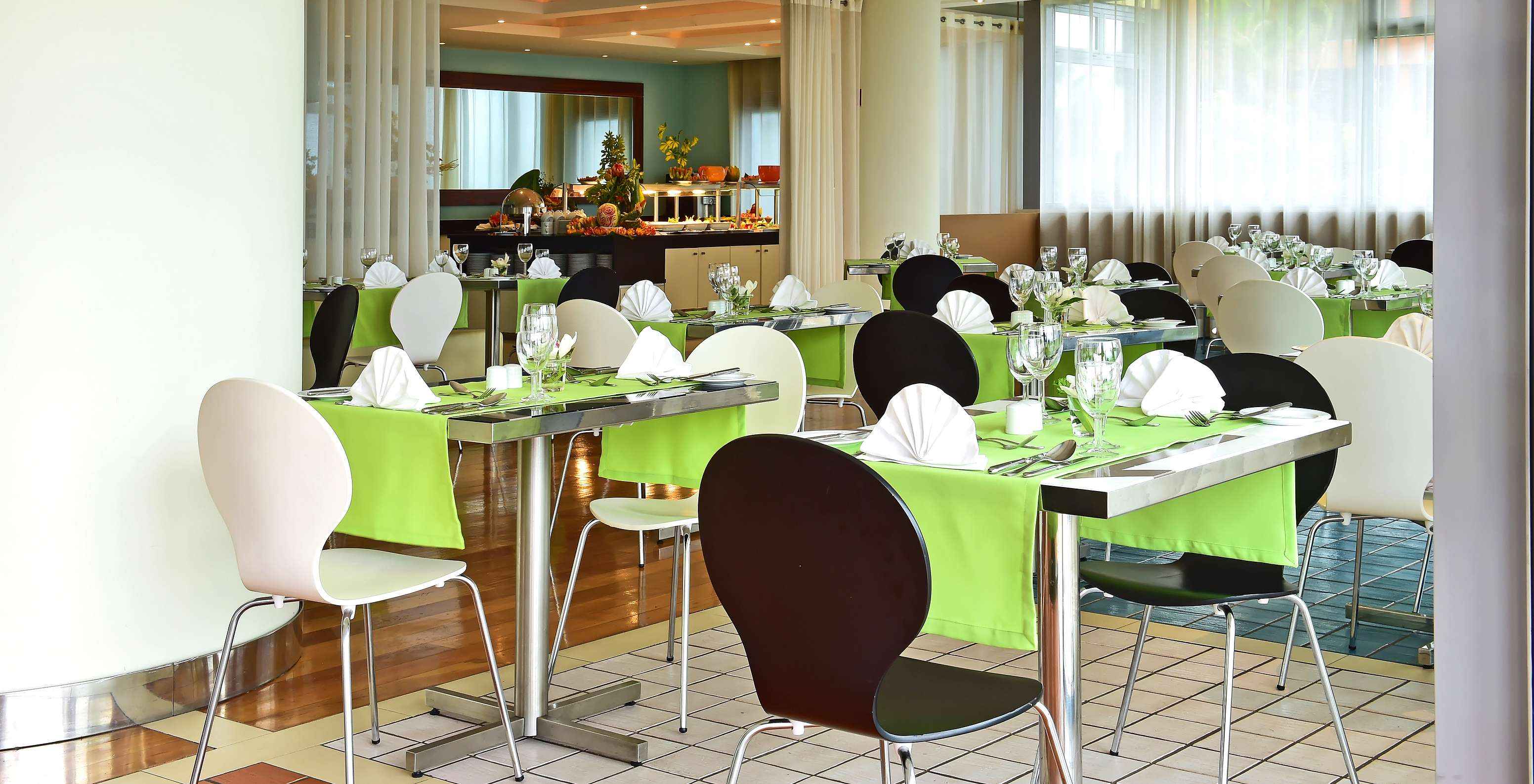 El restaurante Breezes, del Hotel 4 Estrellas Junto al Mar en Funchal, tiene varias mesas con mantel verde y buffet