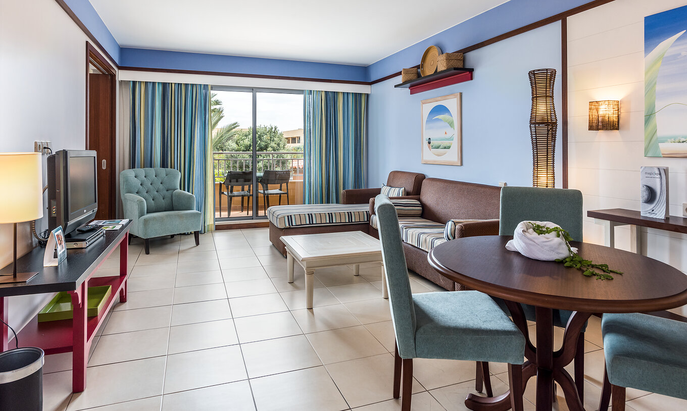 La Suite Apartamento T2 del Pestana Porto Santo All Inclusive tiene una sala con dos sofás, televisión y acceso al balcón