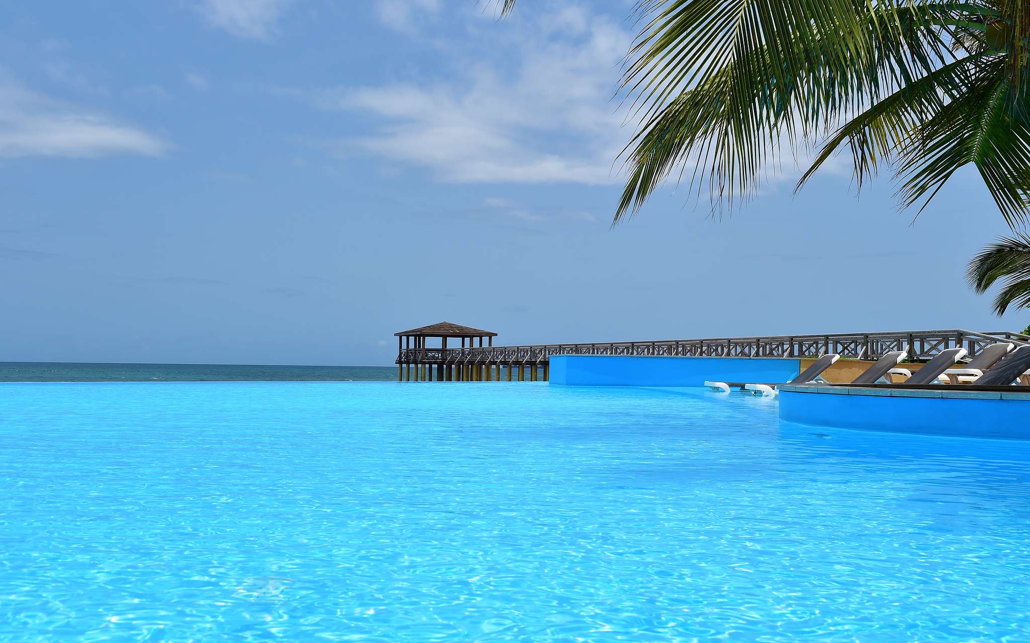 Vista paradisíaca de la piscina Pestana São Tomé que se funde con el mar cristalino un escenario tropical