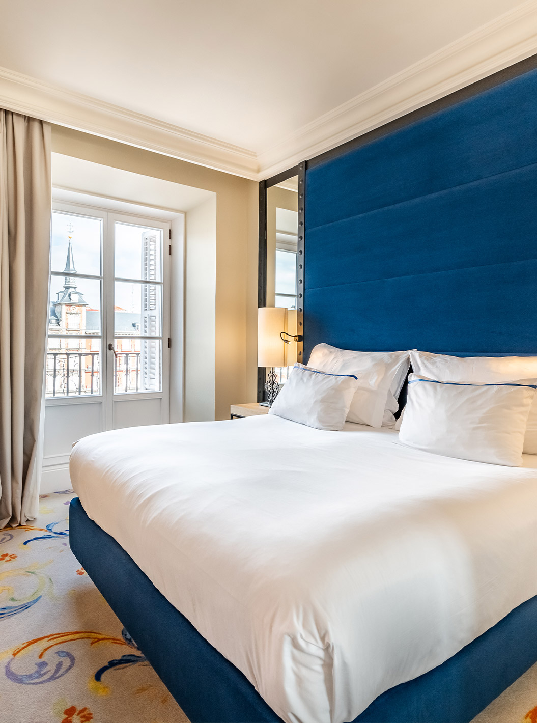 El Deluxe Plaza Mayor del Pestana Plaza Mayor Madrid tiene una cama de casal, dos mesas de noche y un espejo en la pared