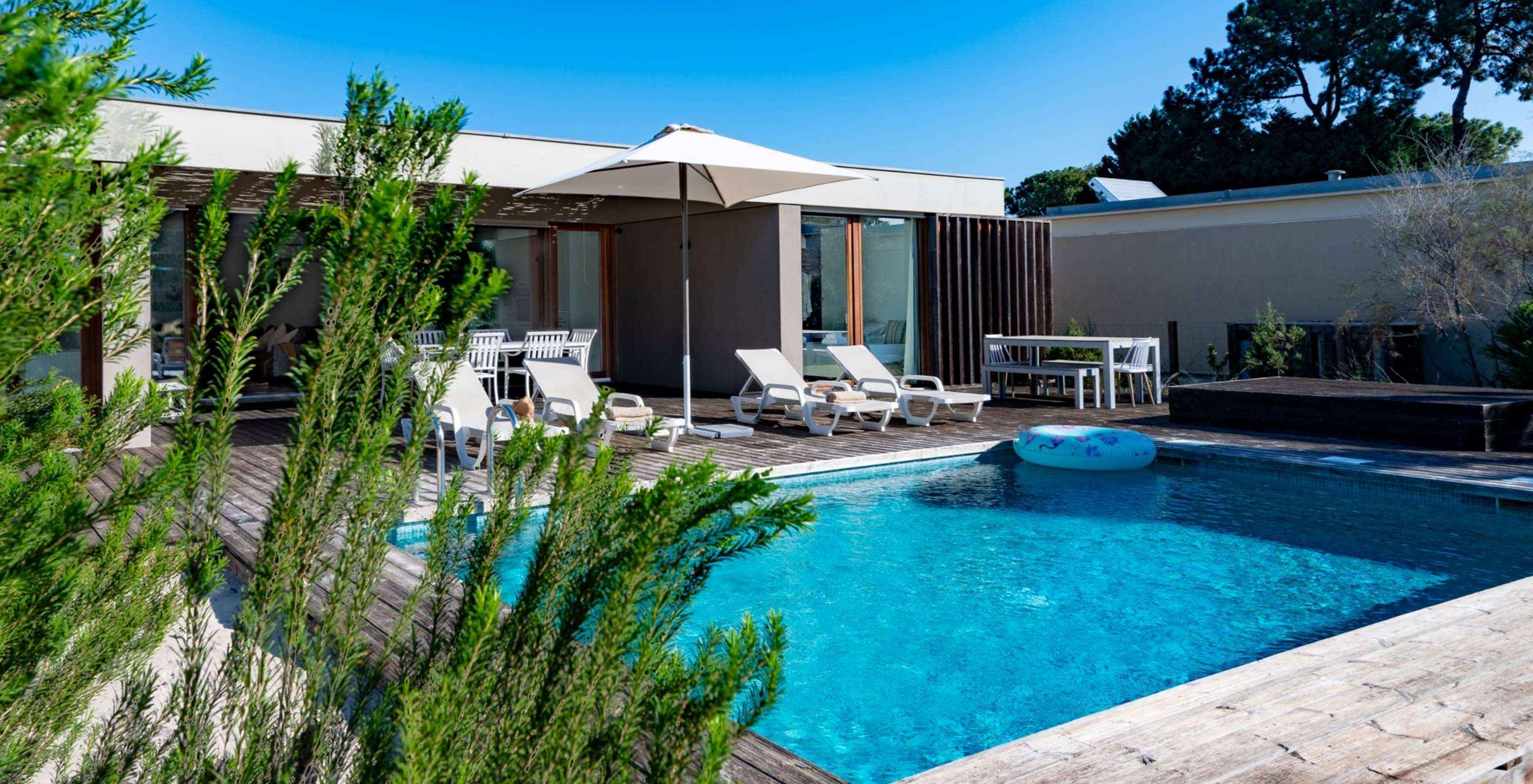 De Villas met 4 Slaapkamers van Pestana Tróia Eco Resort hebben verschillende ligstoelen en een parasol