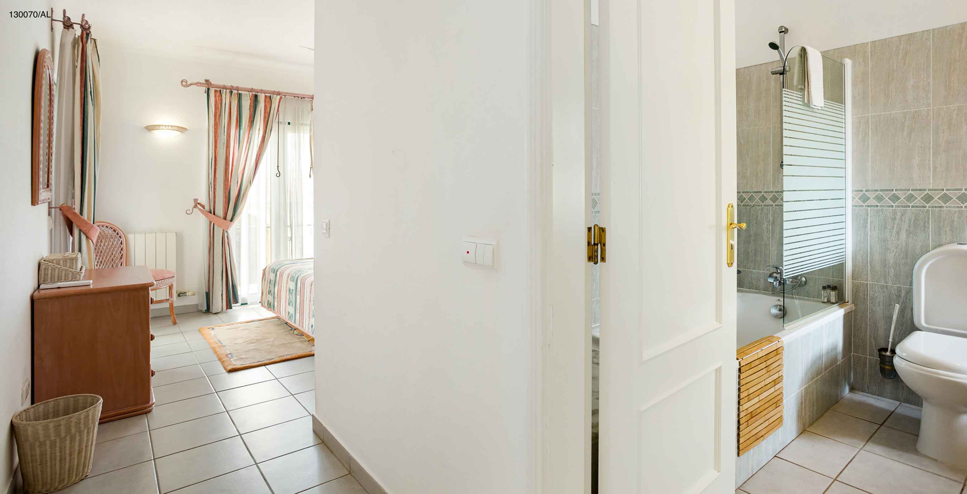 Het appartement Pestana Carvoeiro Golf T2 Superior heeft een slaapkamer met een badkamer en een houten kast