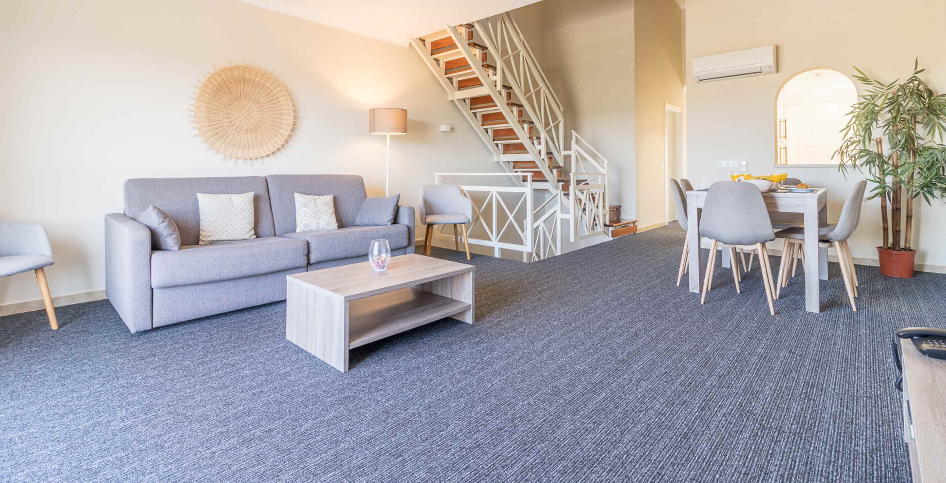 Het tweeslaapkamerappartement bij Pestana Gramacho heeft een salon met grijze sofa, tafel en trap achteraan