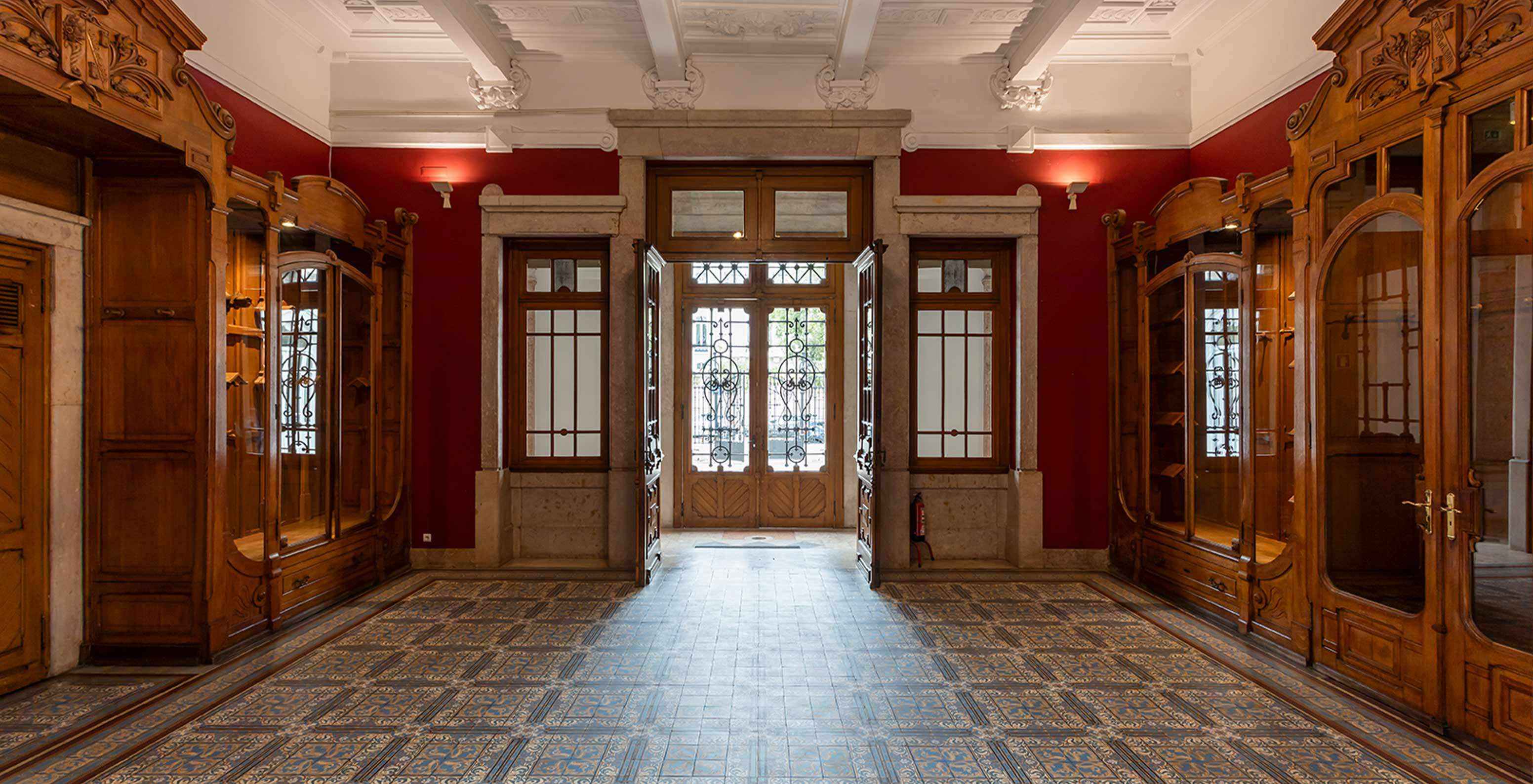 Pestana Palace Lisboa heeft een evenementenruimte met rode muren en antiek houten meubilair	