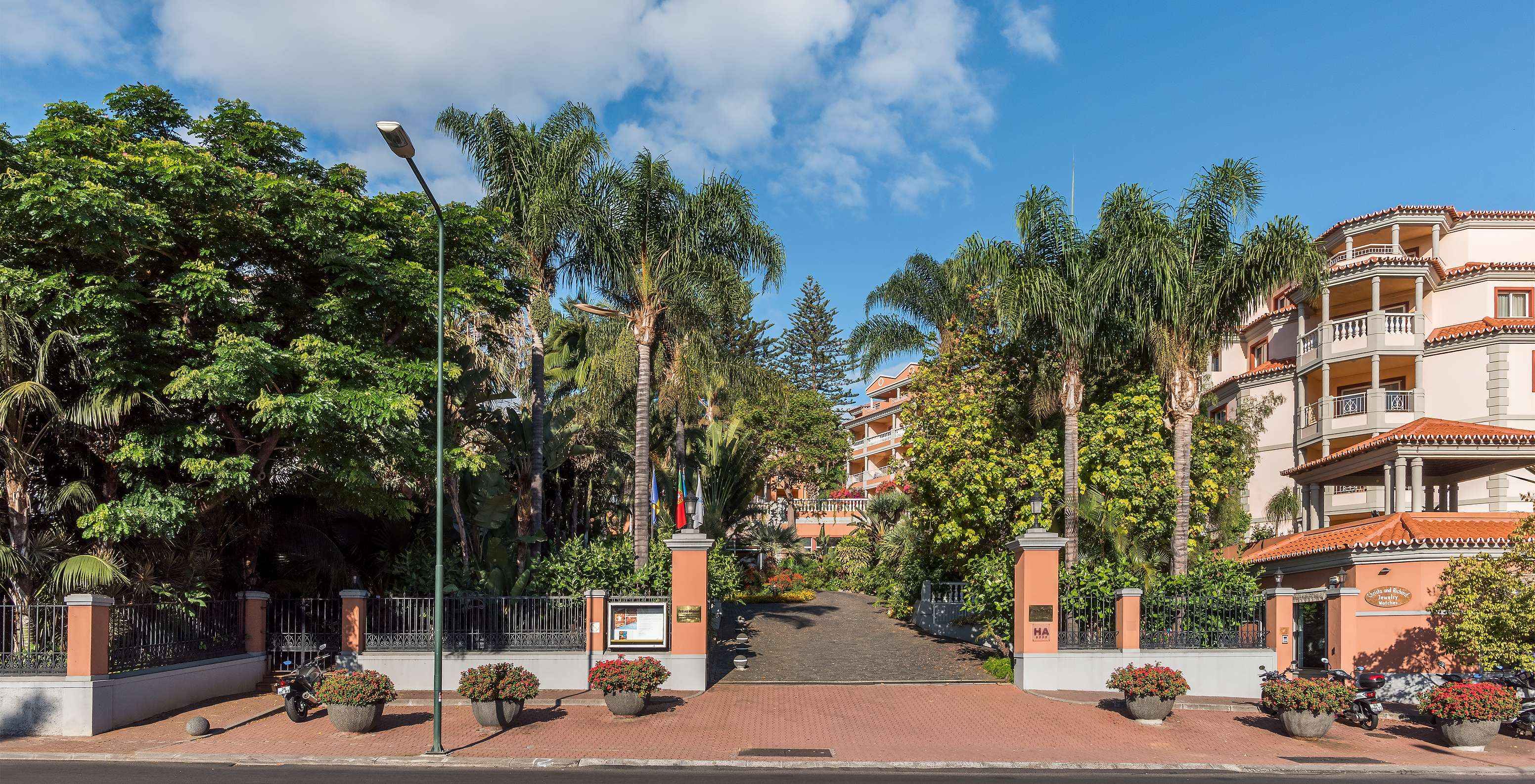 Ingang van Pestana Village, een romantisch hotel in Funchal, Madeira, met verschillende palmbomen en oranje gebouwen
