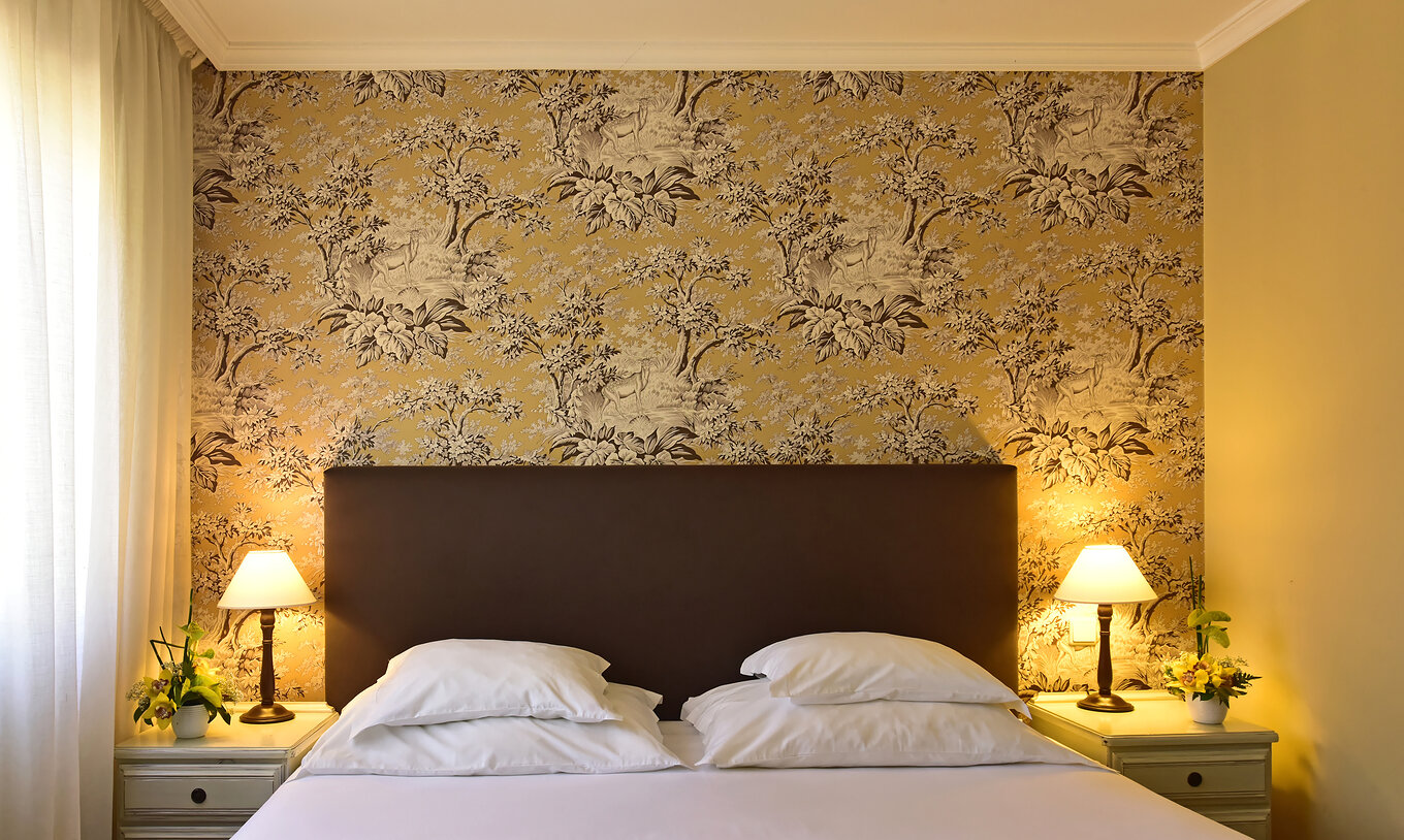 De Twin superior met Jacuzzi van Pestana Village heeft een tweepersoonsbed met hoofdeinde en kastanjebruin dekbed en behang