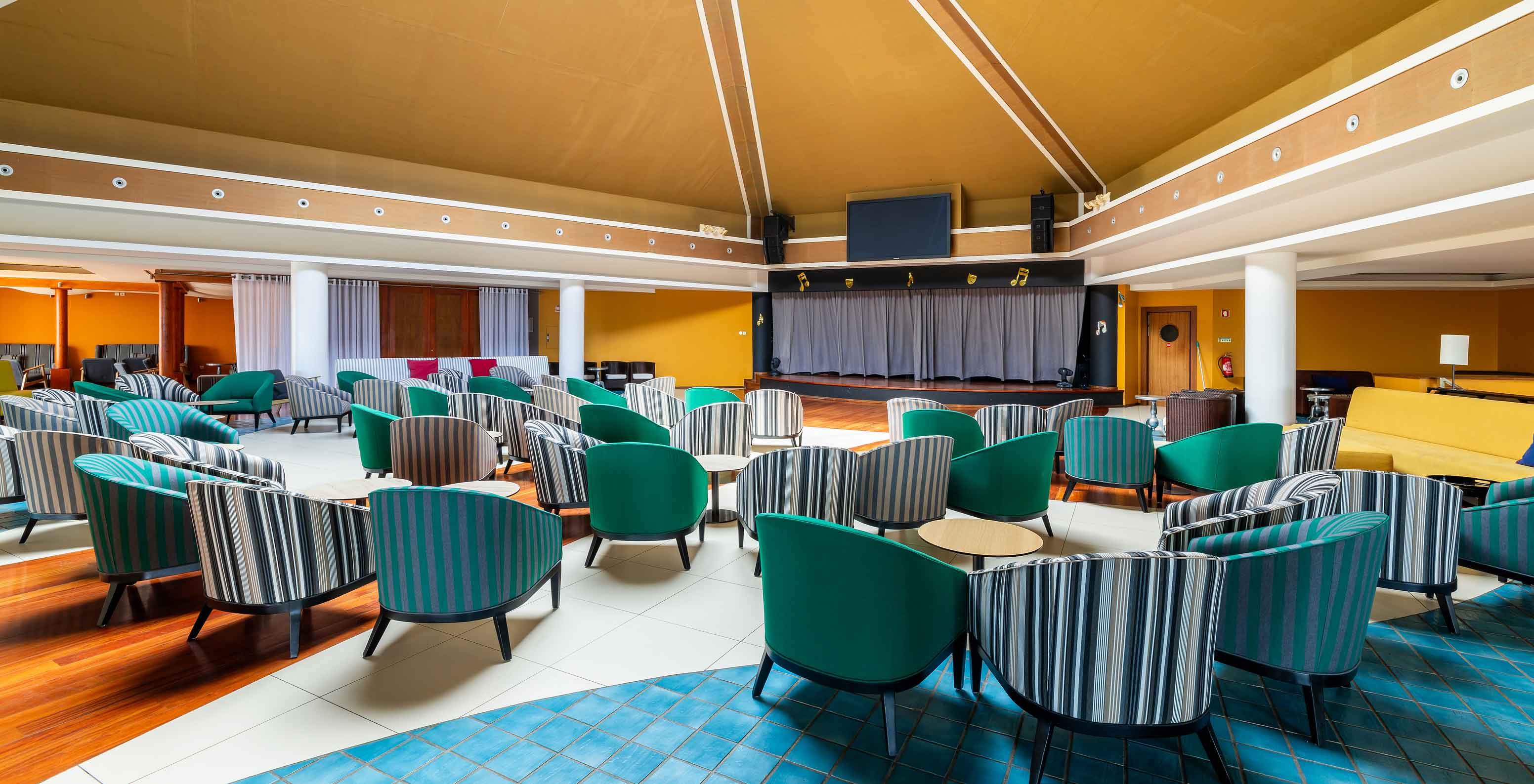 Bar Sunset van het 5-sterrenresort op Porto Santo heeft een ruime ruimte met gele muren en groene stoelen.