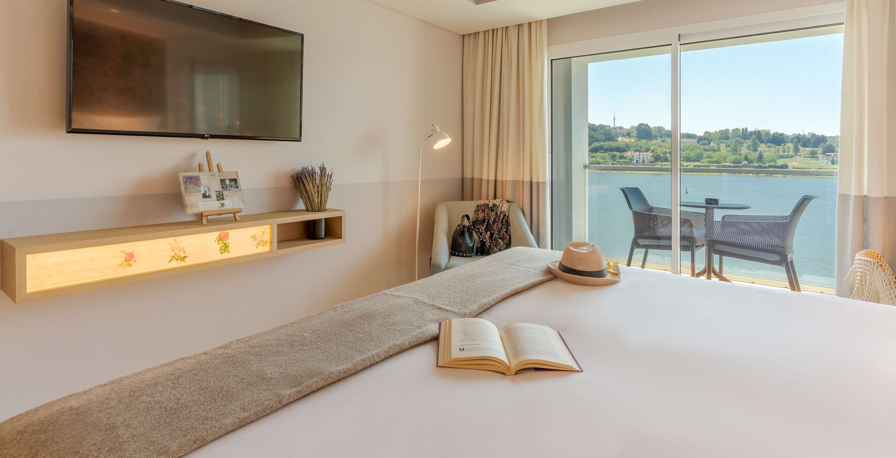 De Deluxe River View kamer van Pestana Douro Riverside heeft een tweepersoonsbed, televisie en een fauteuil