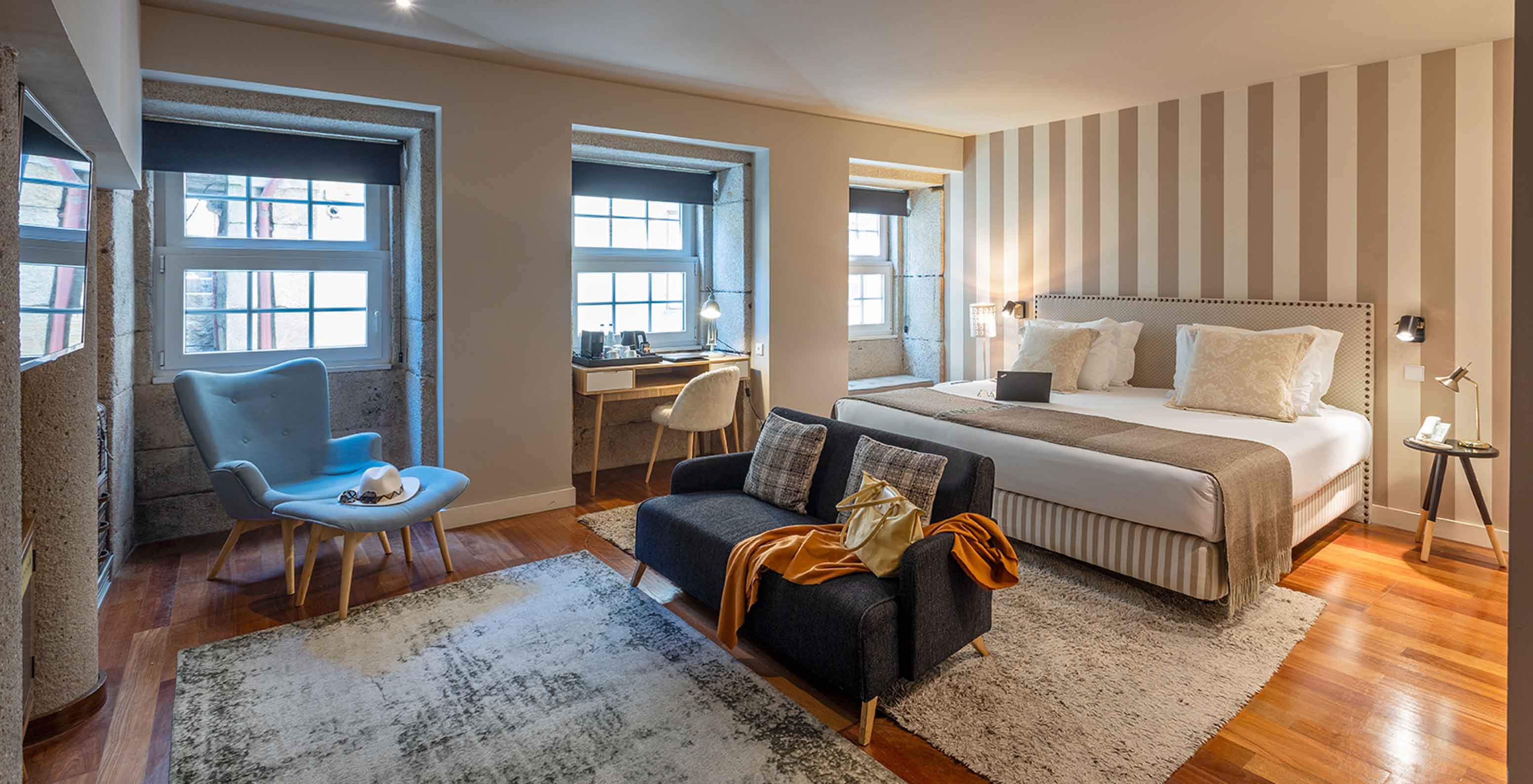 De Heritage Suite van het Pestana Vintage Porto heeft een tweepersoonsbed, twee banken op tapijten en meerdere ramen