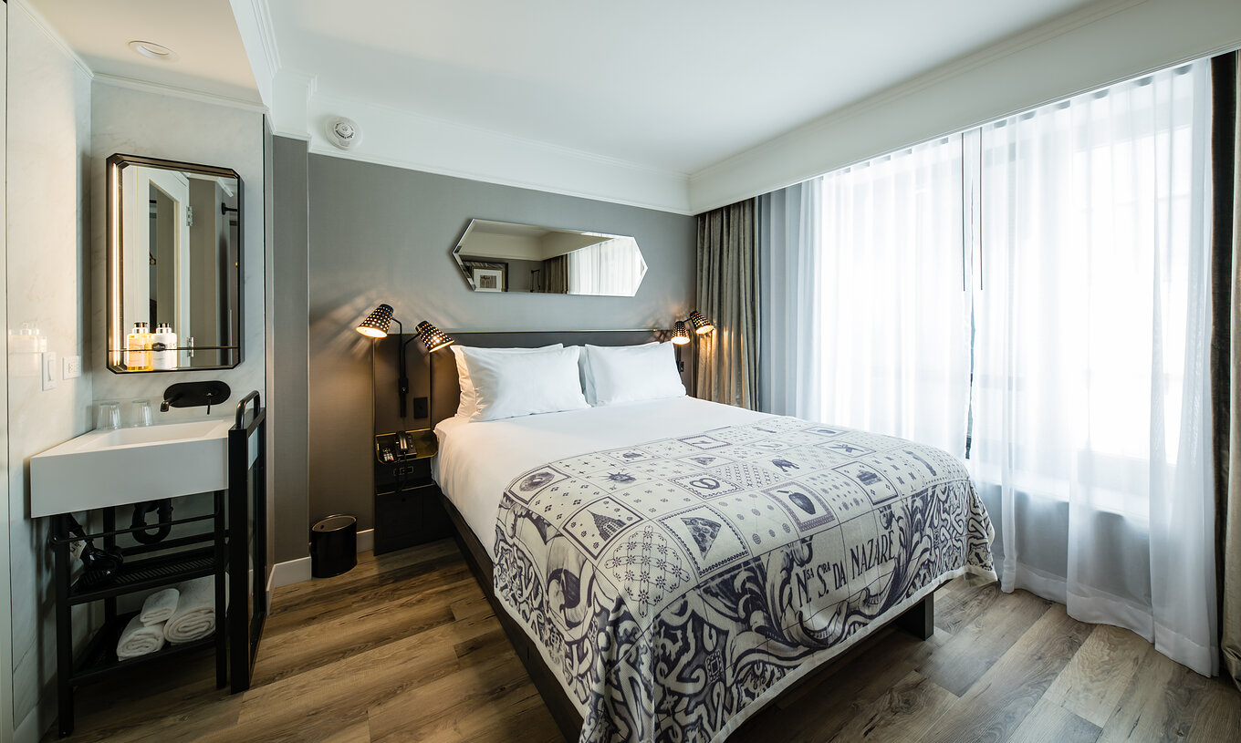 De Superior kamer van Pestana Park Avenue heeft een tweepersoonsbed, met wastafel en spiegel in de kamer, en nachttafel