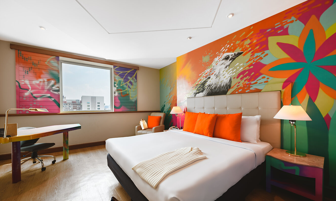 O Art Room do Pestana São Paulo tem uma cama de casal e pinturas coloridas na parede dos artistas Alma Salgada