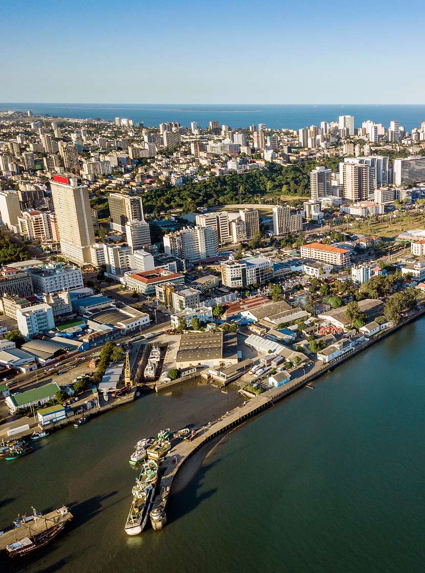 Vista aérea da cidade de Maputo, capital de Moçambique, com várias concentrações de prédios e mar em seu redor