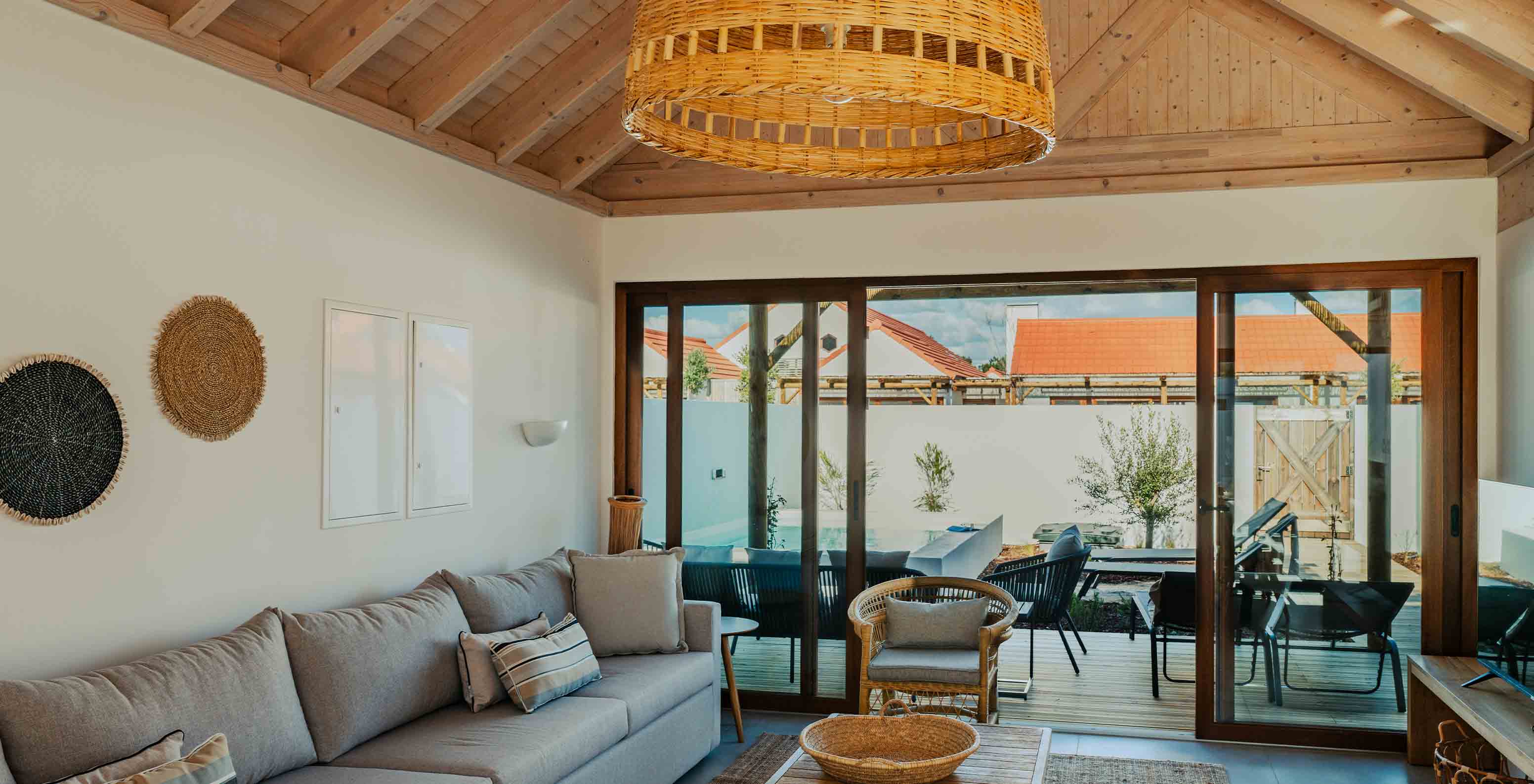 A Superior Villa do Pestana Comporta Village Residences tem uma sala de estar com um sofá cinza e uma varanda ao fundo