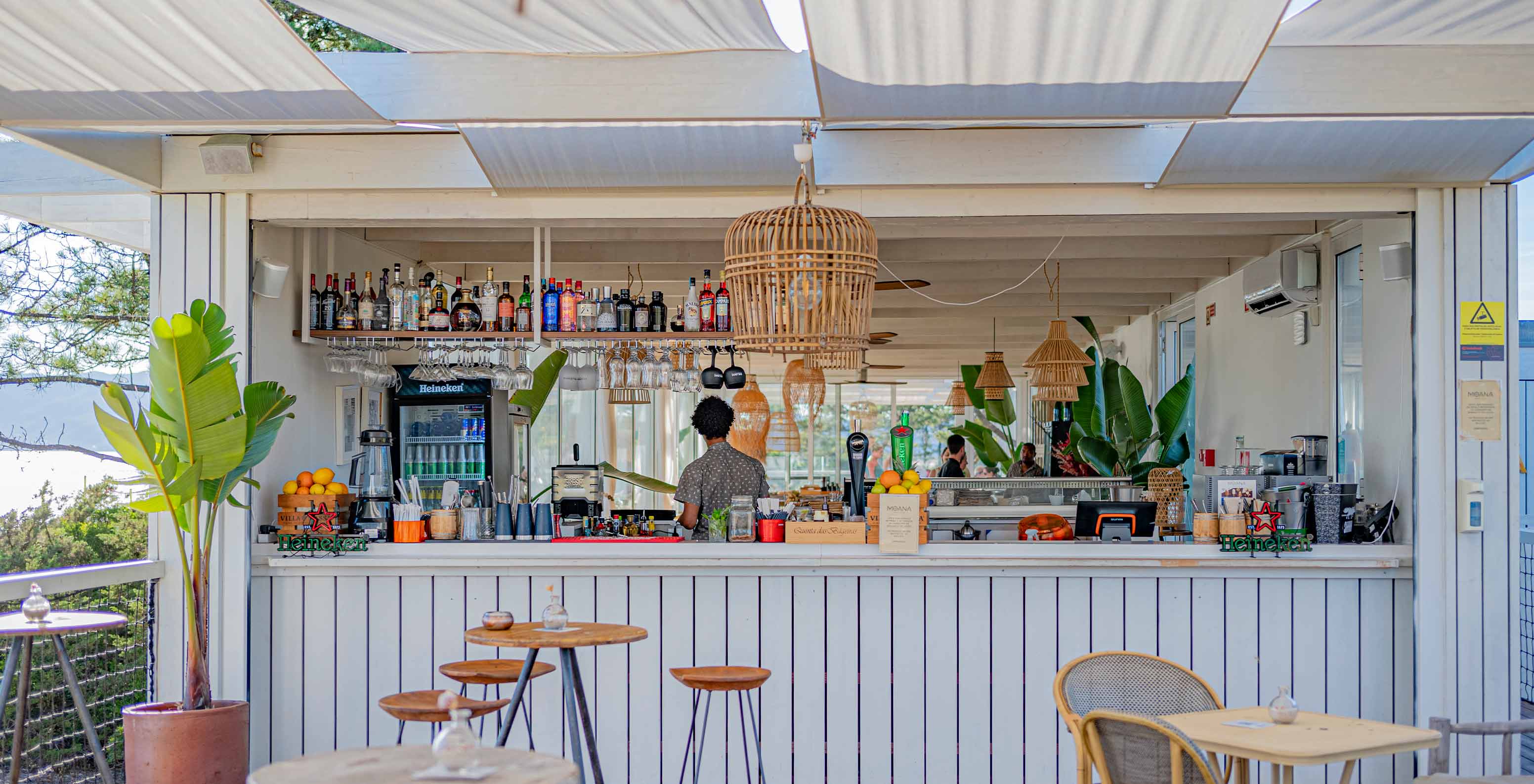 O bar Moana Beach Club,  bar de praia do Pestana Tróia Eco Resort tem mesas de madeira, cadeiras e um balcão com bebidas 