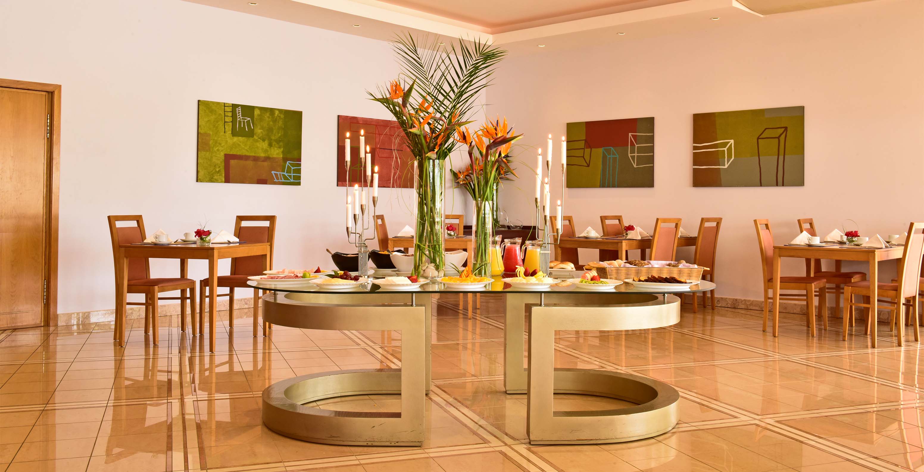 O restaurante A Adega, do Aparthotel no Algarve, tem mesas e cadeiras, quadros na parede e uma mesa central com comida