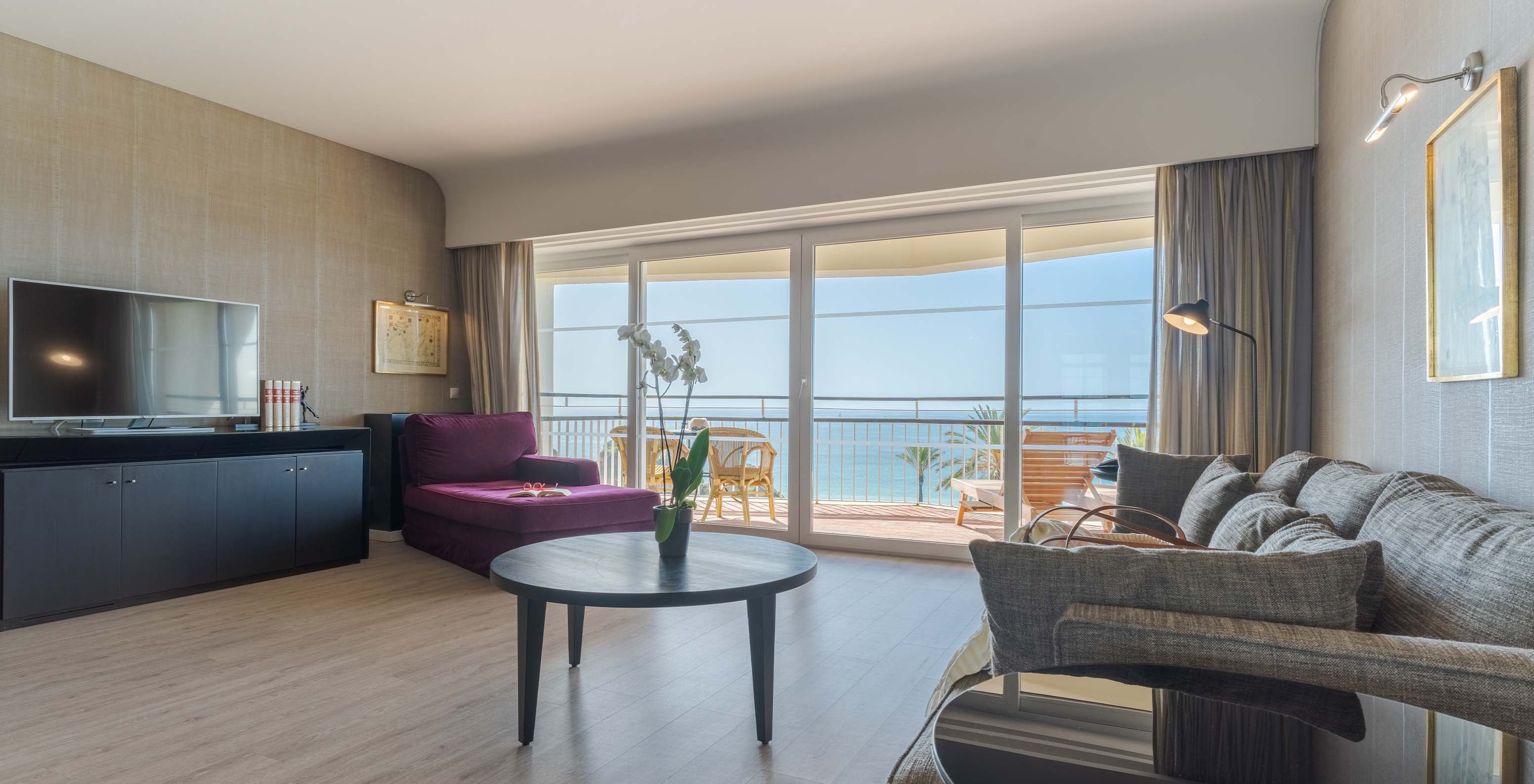 A Suite Luxo Vista Mar do Pestana Alvor Praia tem uma sala com sofá, poltrona, mesa, televisão e varanda com vista mar