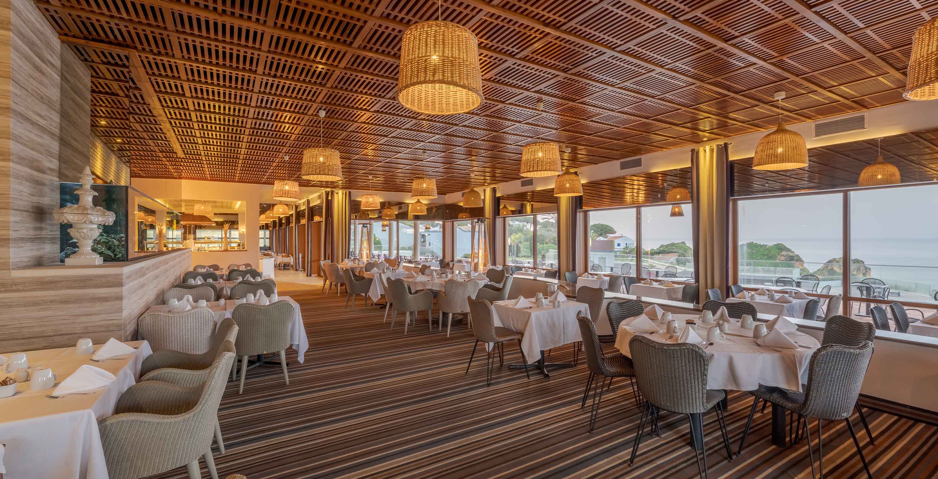 O restaurante Almofariz, do Hotel 5 Estrelas no Algarve, com ripas de madeira no teto, aquário e vista para o mar