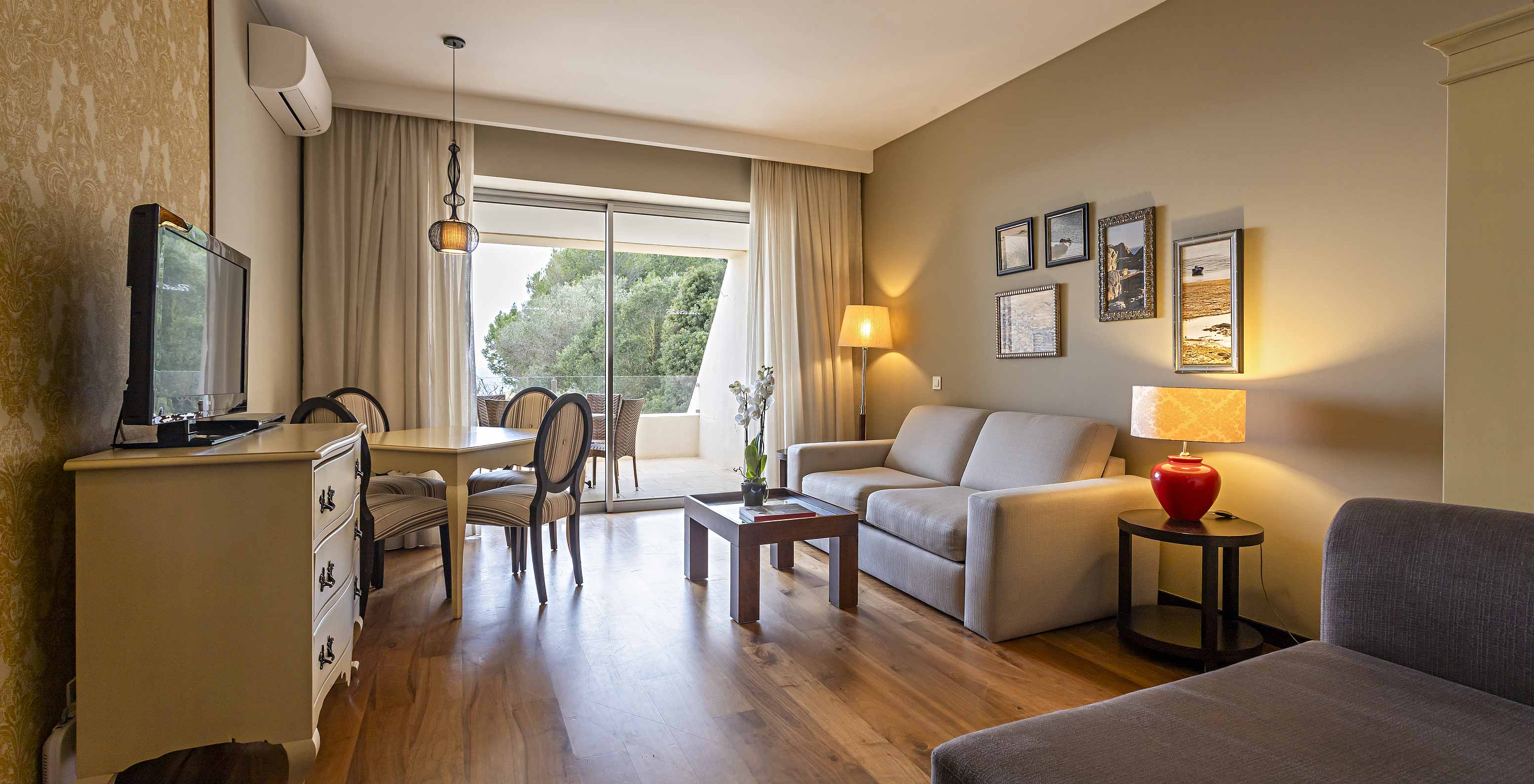 A Cliff Suite T1 do Pestana Alvor Praia tem uma sala com dois sofás, uma cómoda com televisão, uma mesa de jantar e cadeiras