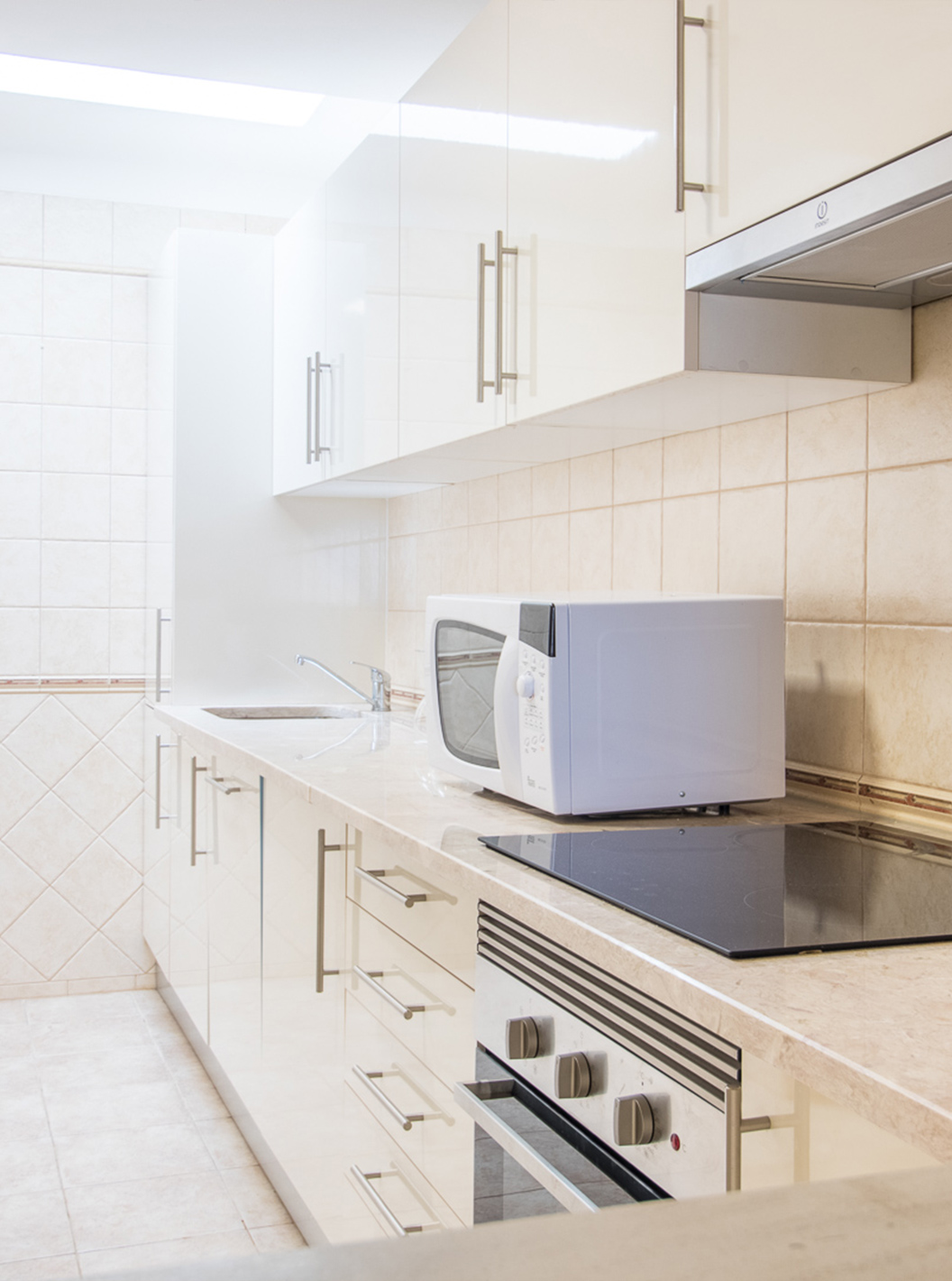 O Apartamento T2 do Pestana Gramacho Residences tem uma cozinha simples com eletrodomésticos e decoração neutra