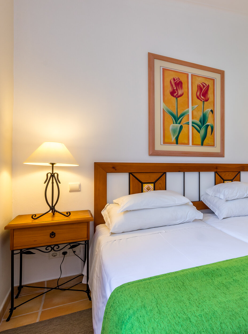 O Apartamento T1 - Terra do Pestana Palm Gardens tem duas camas juntas, com colcha verde e um quadro com duas flores