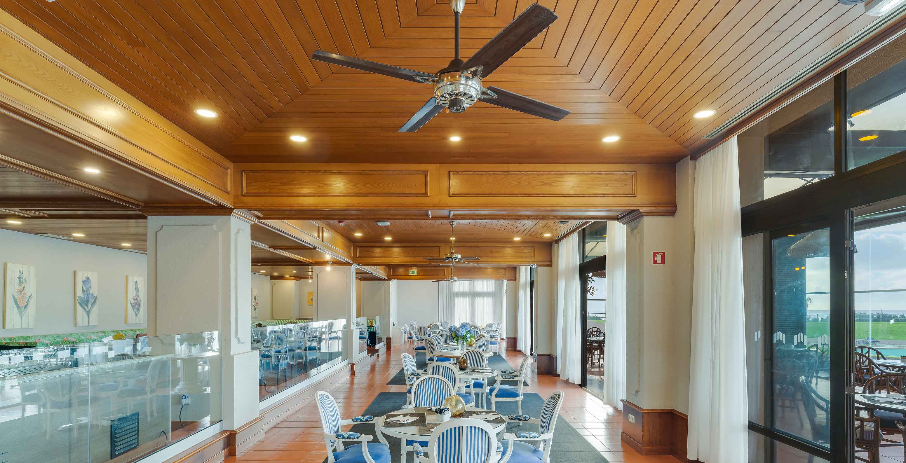 Restaurante Lugar da Praia no Pestana Bahia Praia com mesas, cadeiras, teto em madeira e grandes janelas com vista