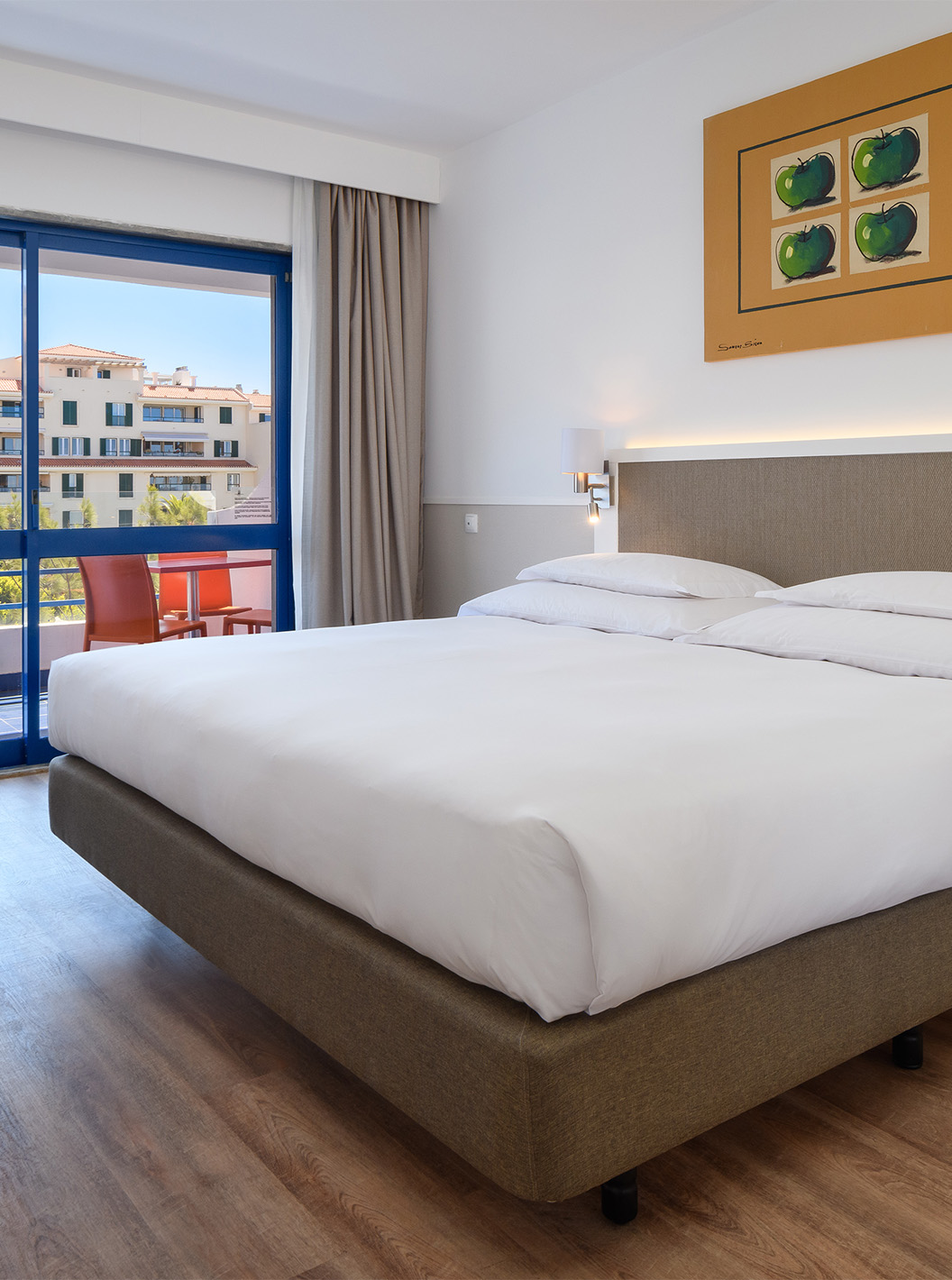 A Suite Deluxe do Pestana Cascais conta com cama de casal, secretária, e um quadro pintado na parede