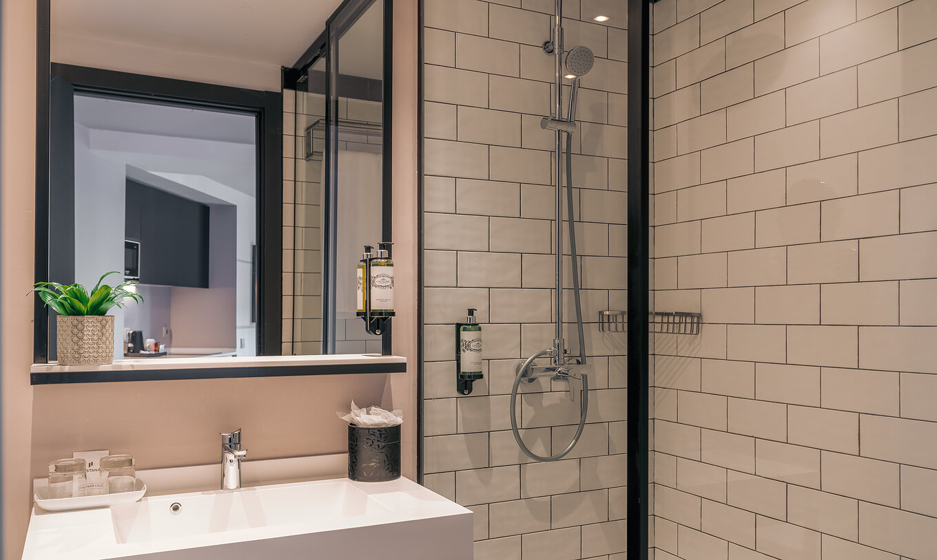 O Double Deluxe Studio do Pestana Lisboa Vintage tem um duche com portas de vidro e detalhes pretos, e um lavatório