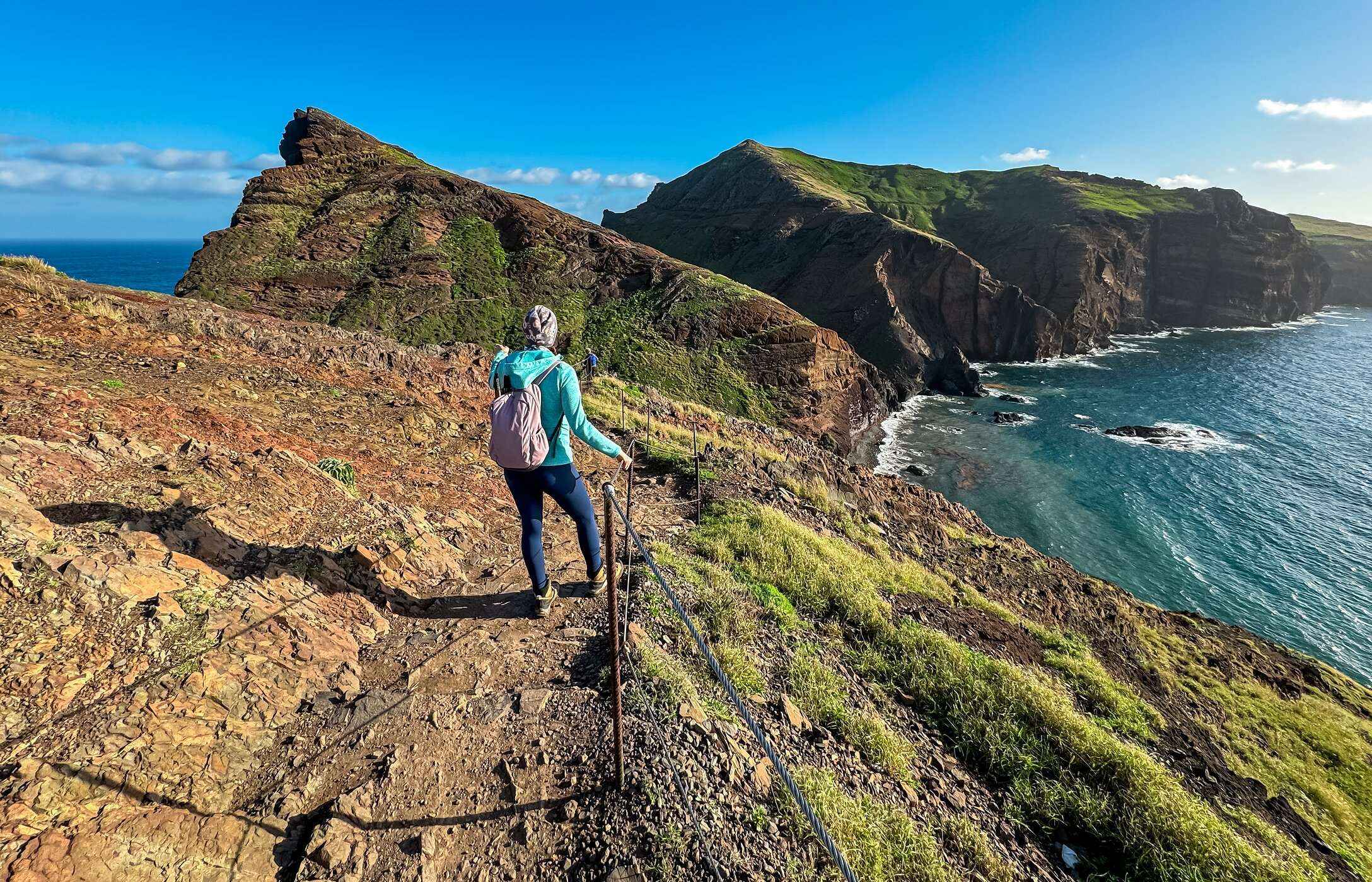 Senhora a fazer um trilho no Funchal, com vista para a montanha e para o oceano Atlântico