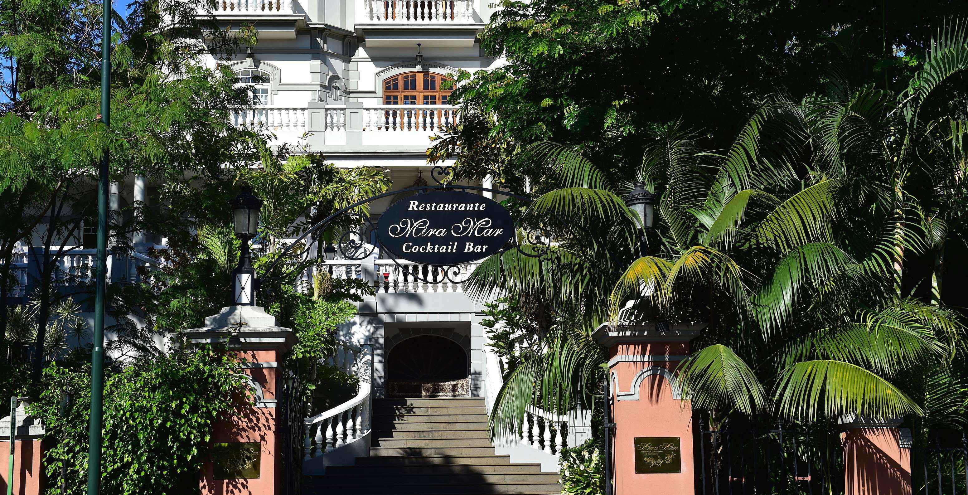 Fachada do restaurante da Quinta Miramar, um edifício branco imponente no meio da vegetação, ideal para eventos