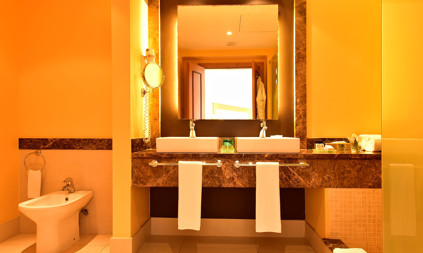 A Suite do Pestana Promenade tem uma casa de banho com um espelho com moldura castanha, dois lavatórios e bidé