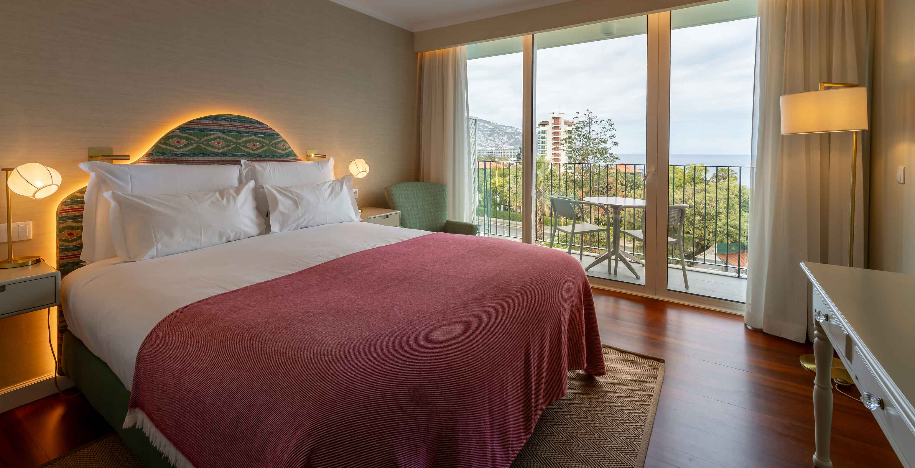 O Quarto Vista Mar Parcial do Pestana Quinta Perestrello tem uma cama de casal, varanda com uma mesa, cadeiras e vista-mar